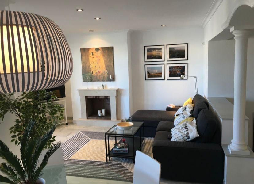 Living room with a dark sofa, abstract rug, fireplace, framed art, and a distinctive hanging light fixture.