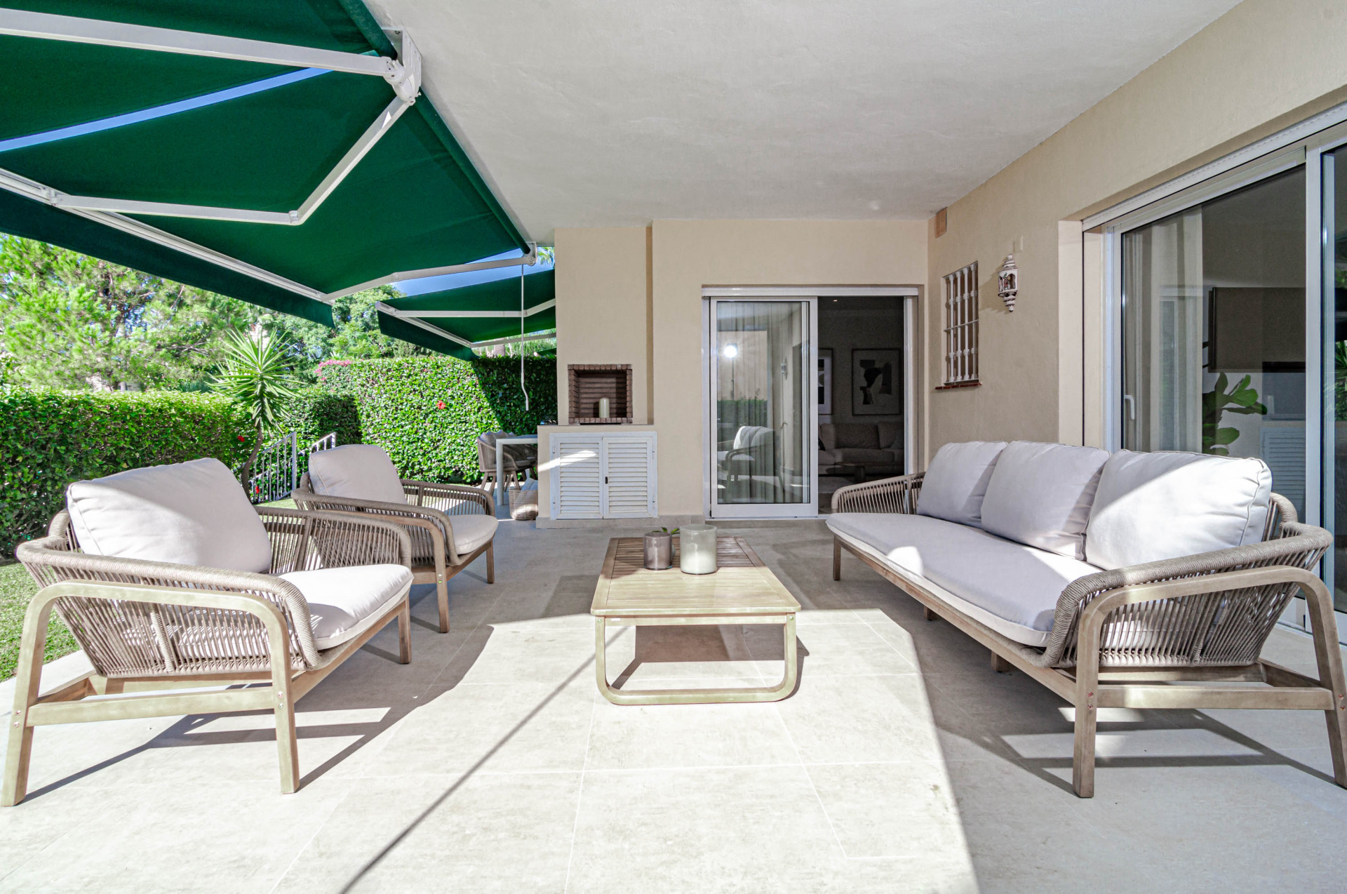 Outdoor patio with a green awning, three seating areas, and a built-in outdoor kitchen with a grill.