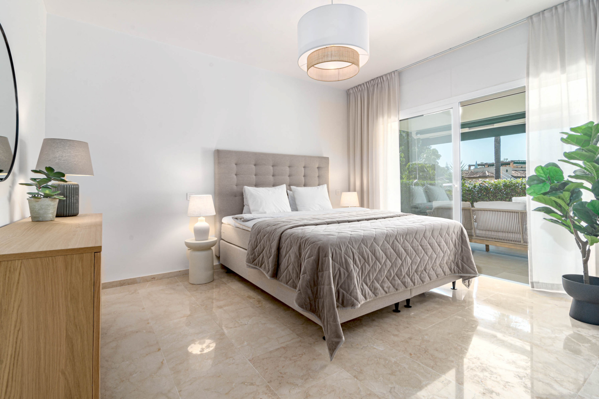 Bedroom with a large bed, two nightstands, dresser, and sliding glass doors leading to a terrace.