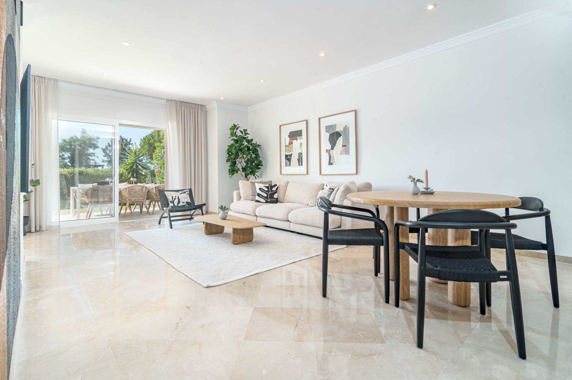 Living room with beige sofa, coffee table, and dining area, leading to an outdoor terrace.