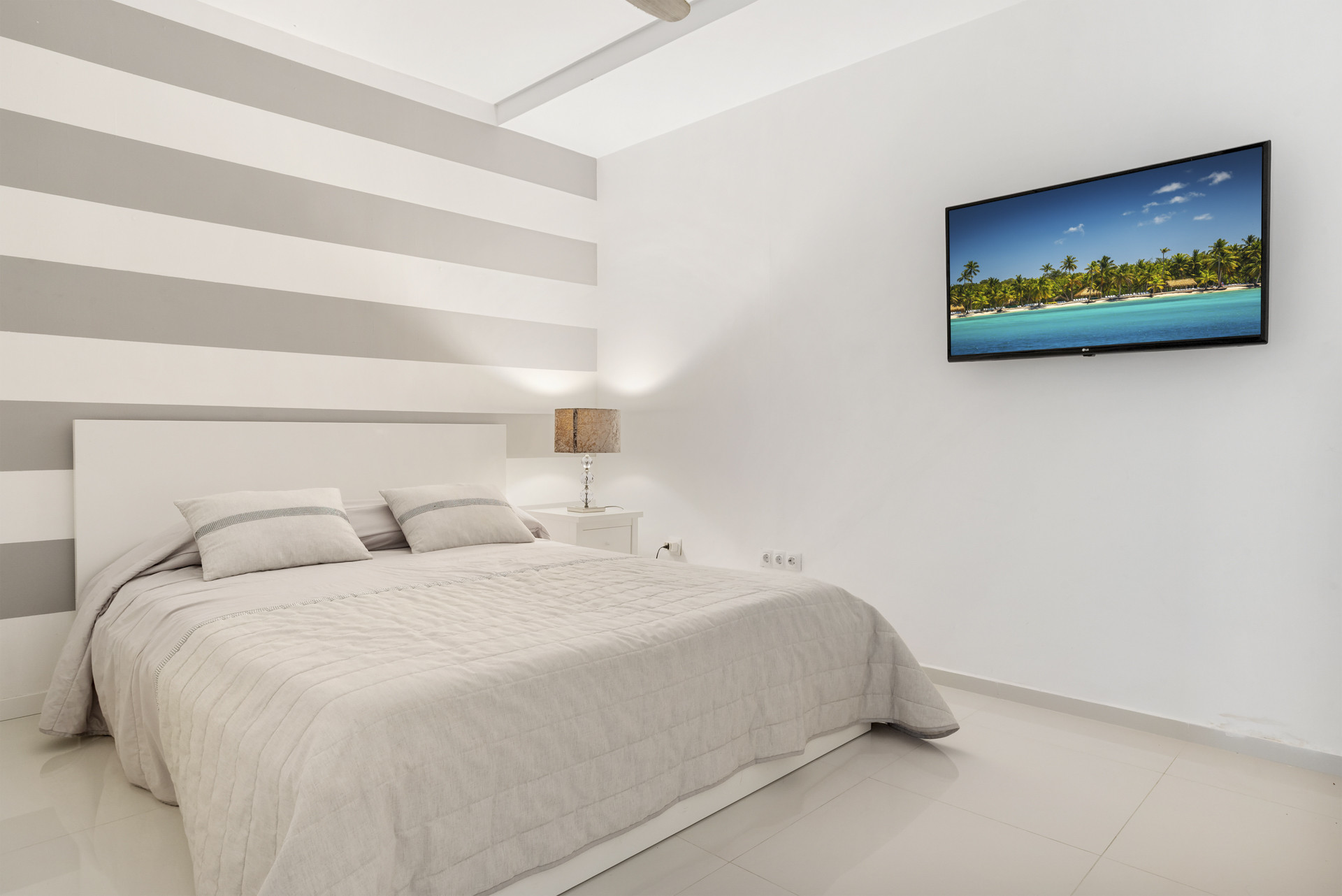 Bedroom with striped walls and a wall-mounted TV.