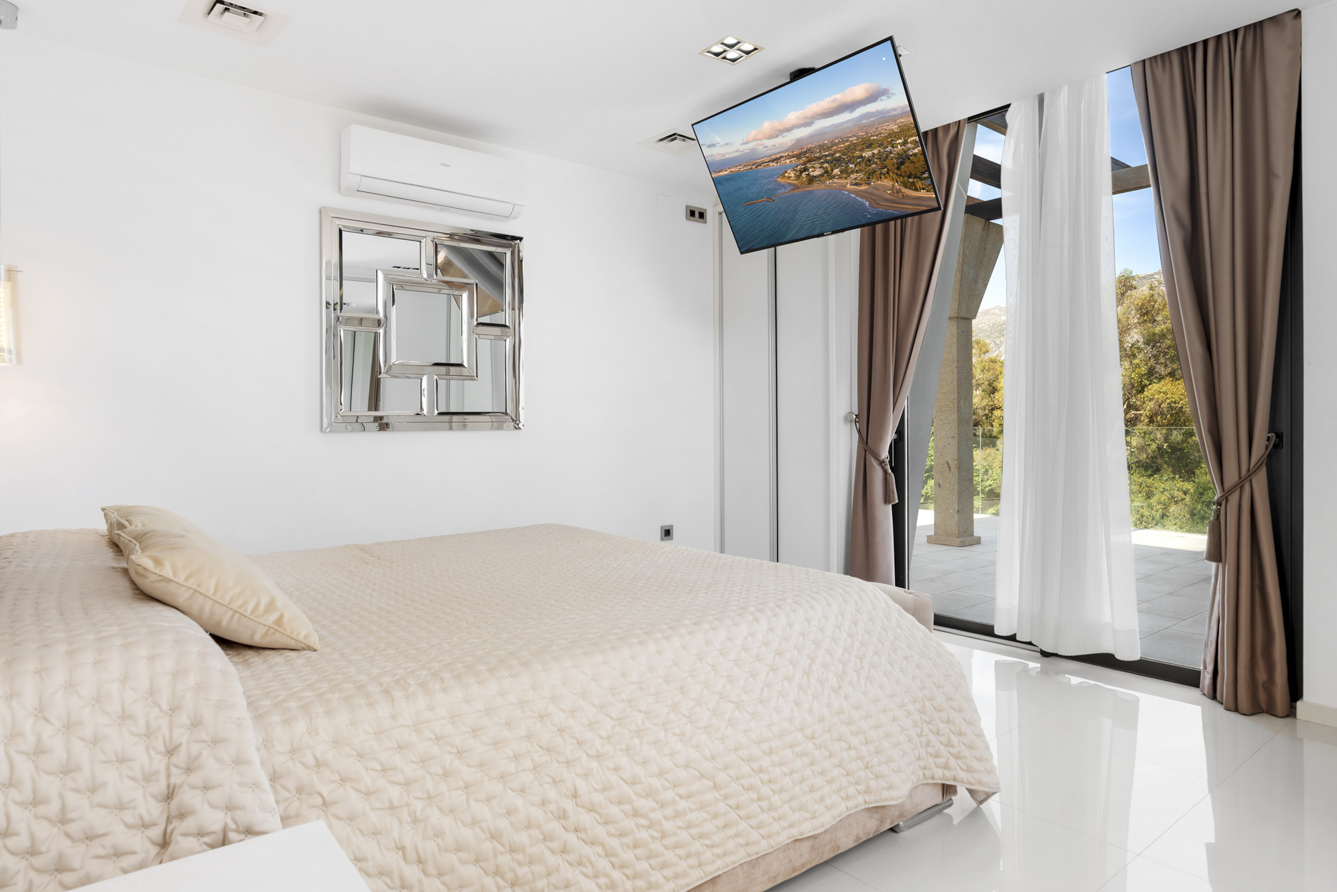 Spacious bedroom with a king-sized bed, mounted TV, and large sliding glass door to terrace.