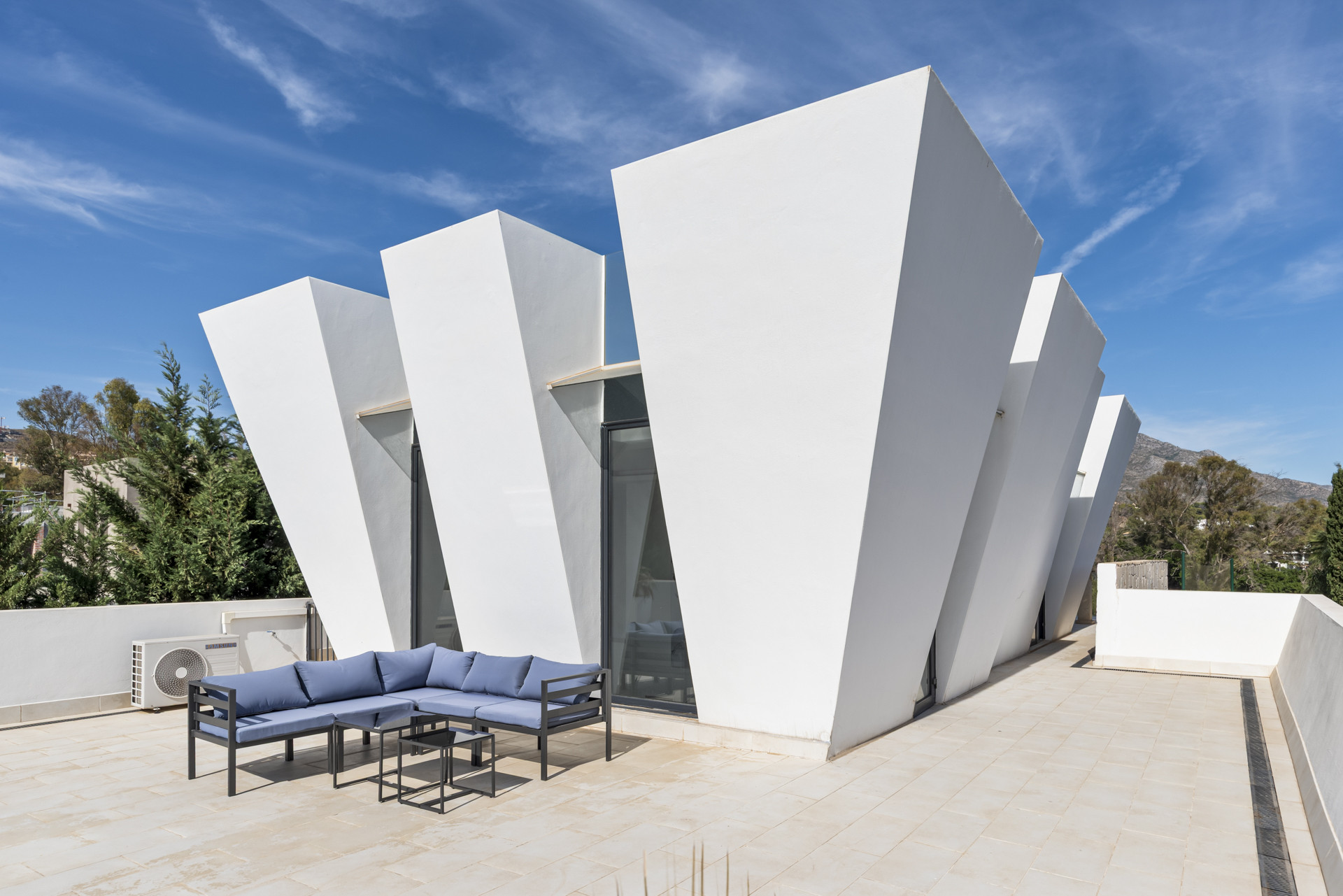 Close-up of unique angular facade of the house with outdoor seating area.
