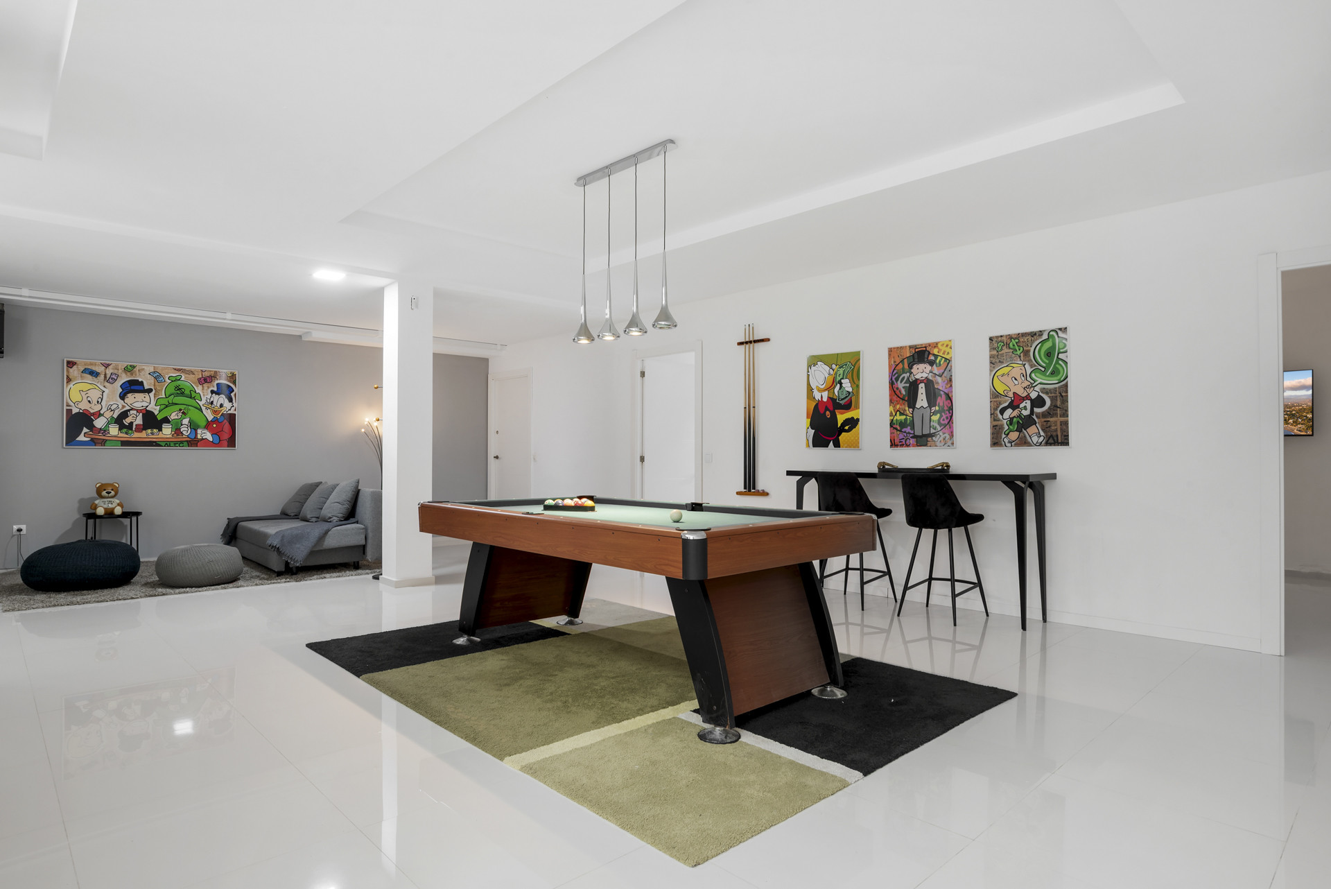 Spacious game room featuring a pool table, two art pieces, and a seating area.