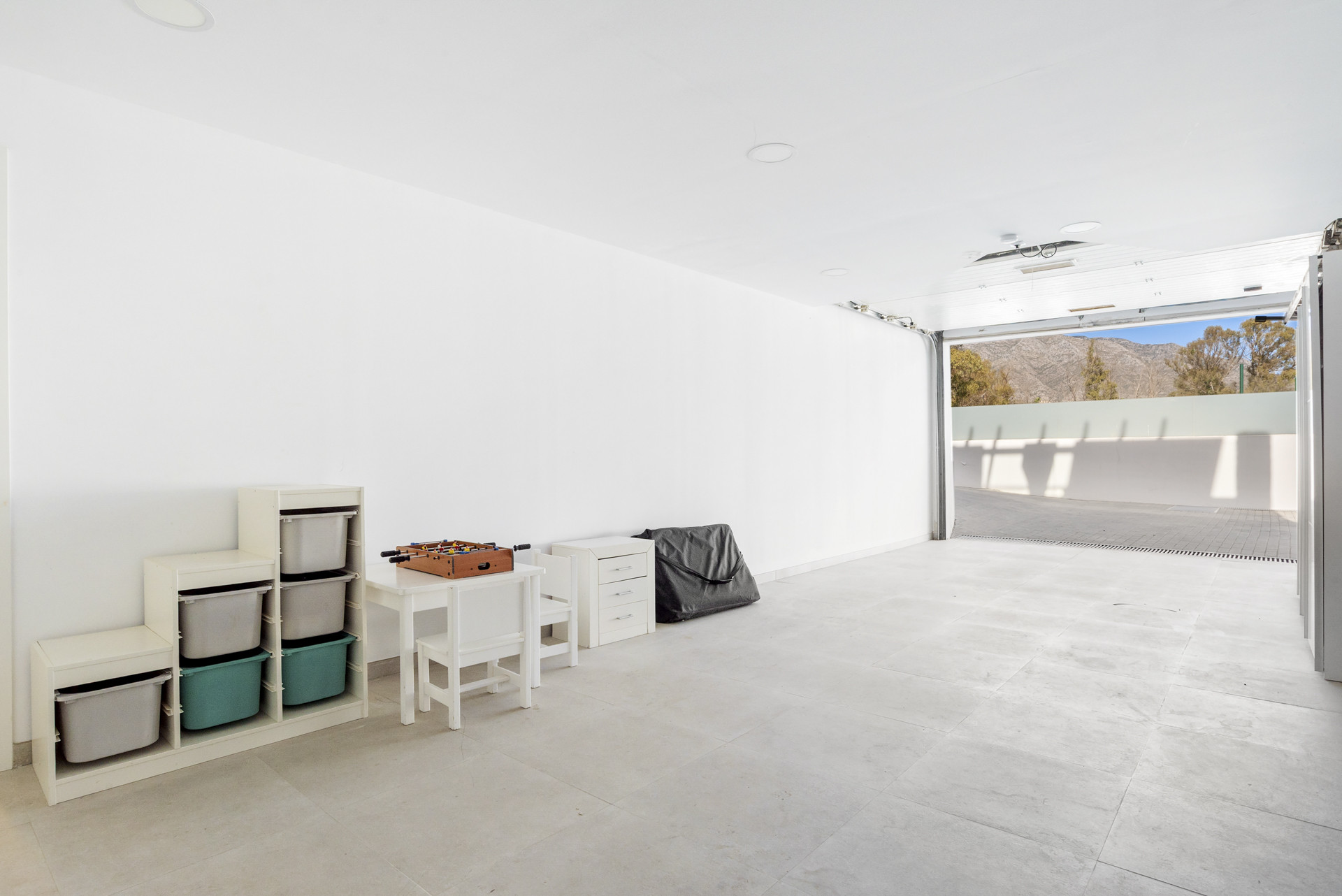 Garage with storage units, a table, and an open door leading to an outdoor view.