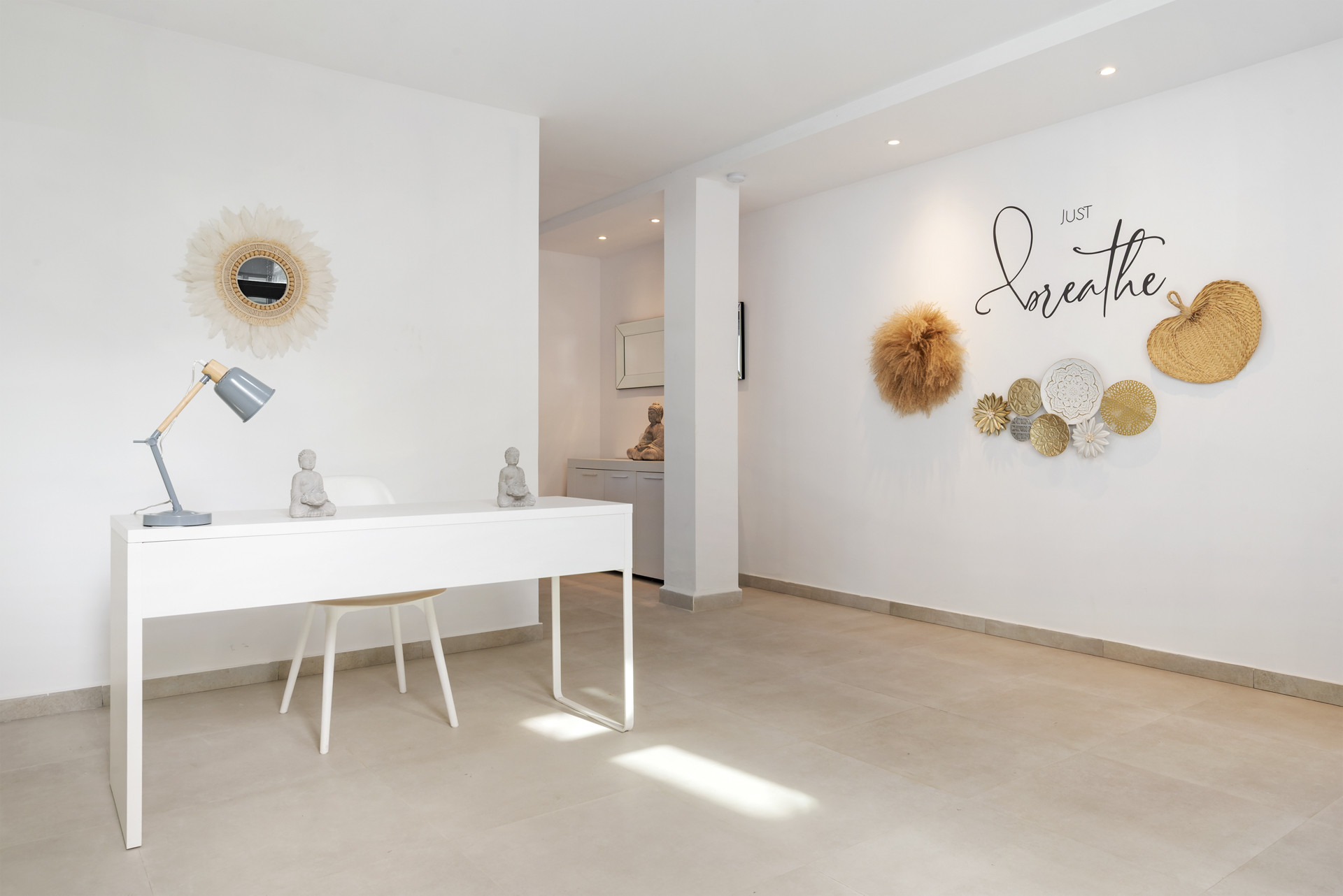 Minimalist office space with a white desk, decorative wall art, and natural light.
