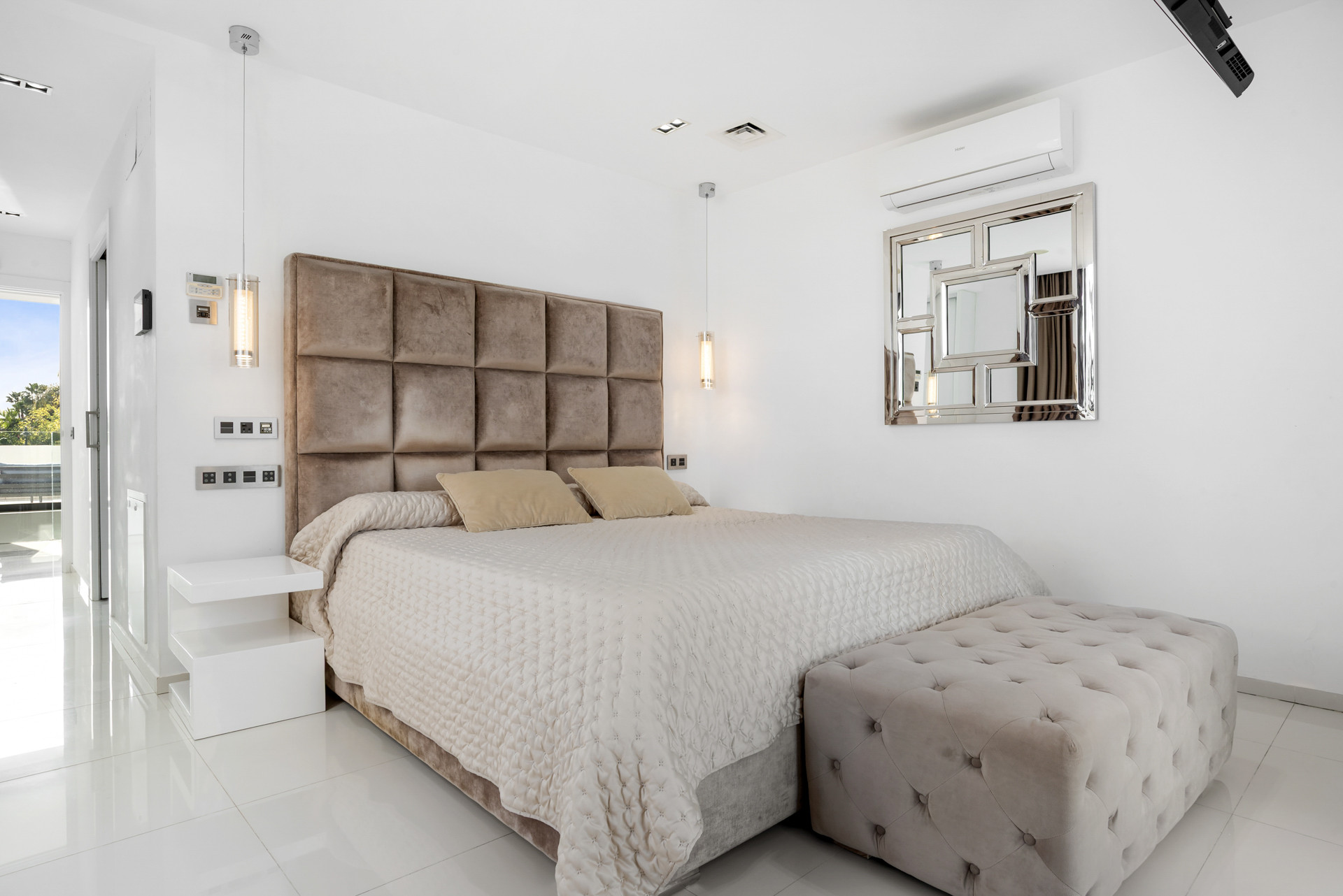 Elegant bedroom with tufted headboard, a comfortable bed, and a stylish ottoman.