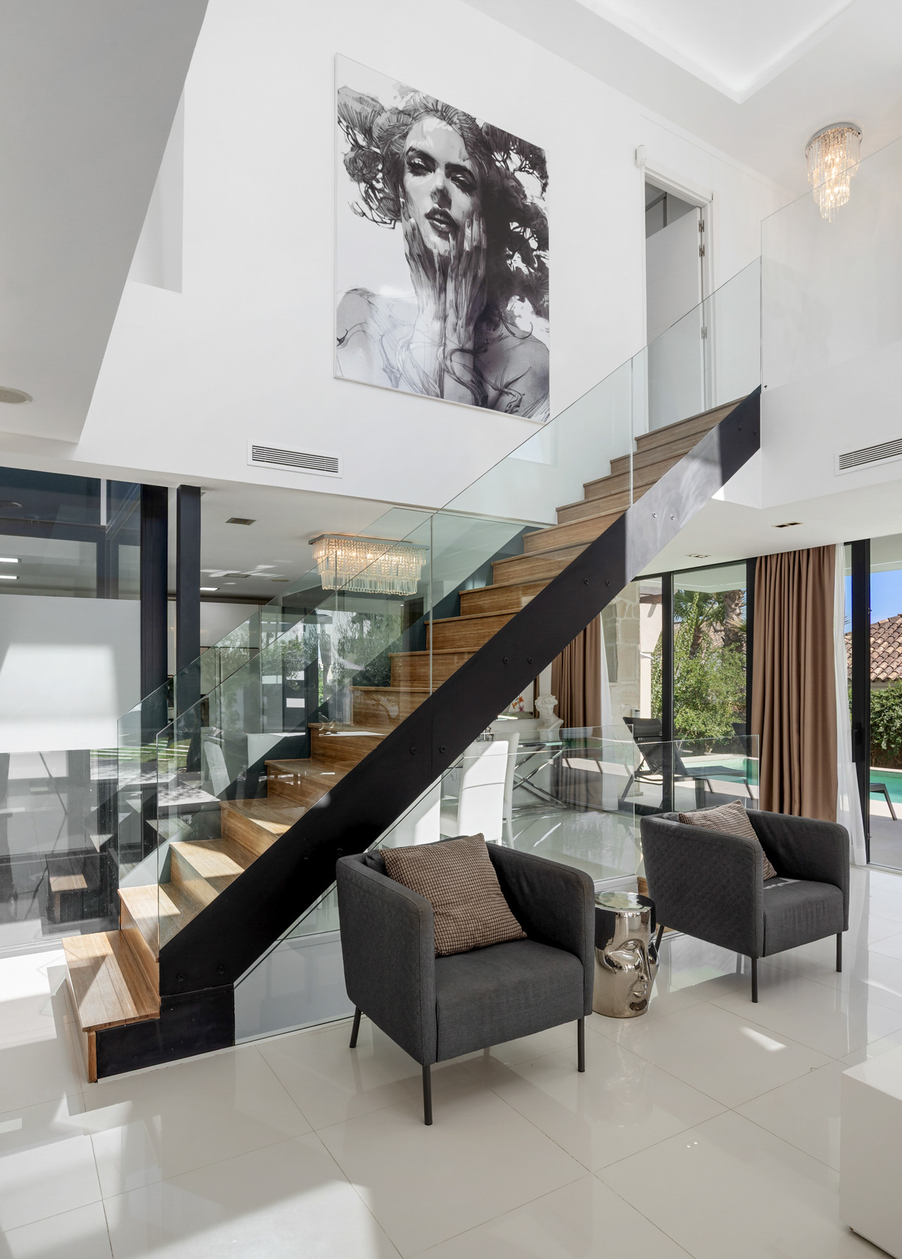 Stylish foyer featuring a staircase, decorative art, chandelier, and two armchairs.