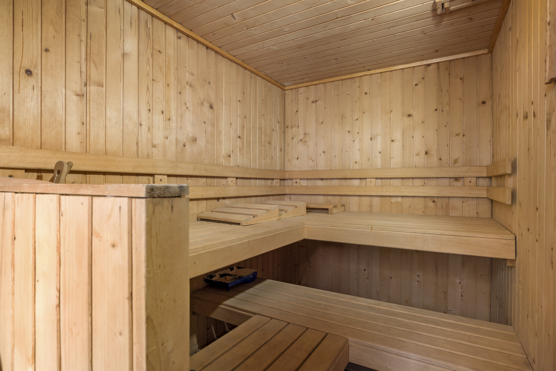 Interior view of a sauna room with multiple wooden benches and slatted walls.