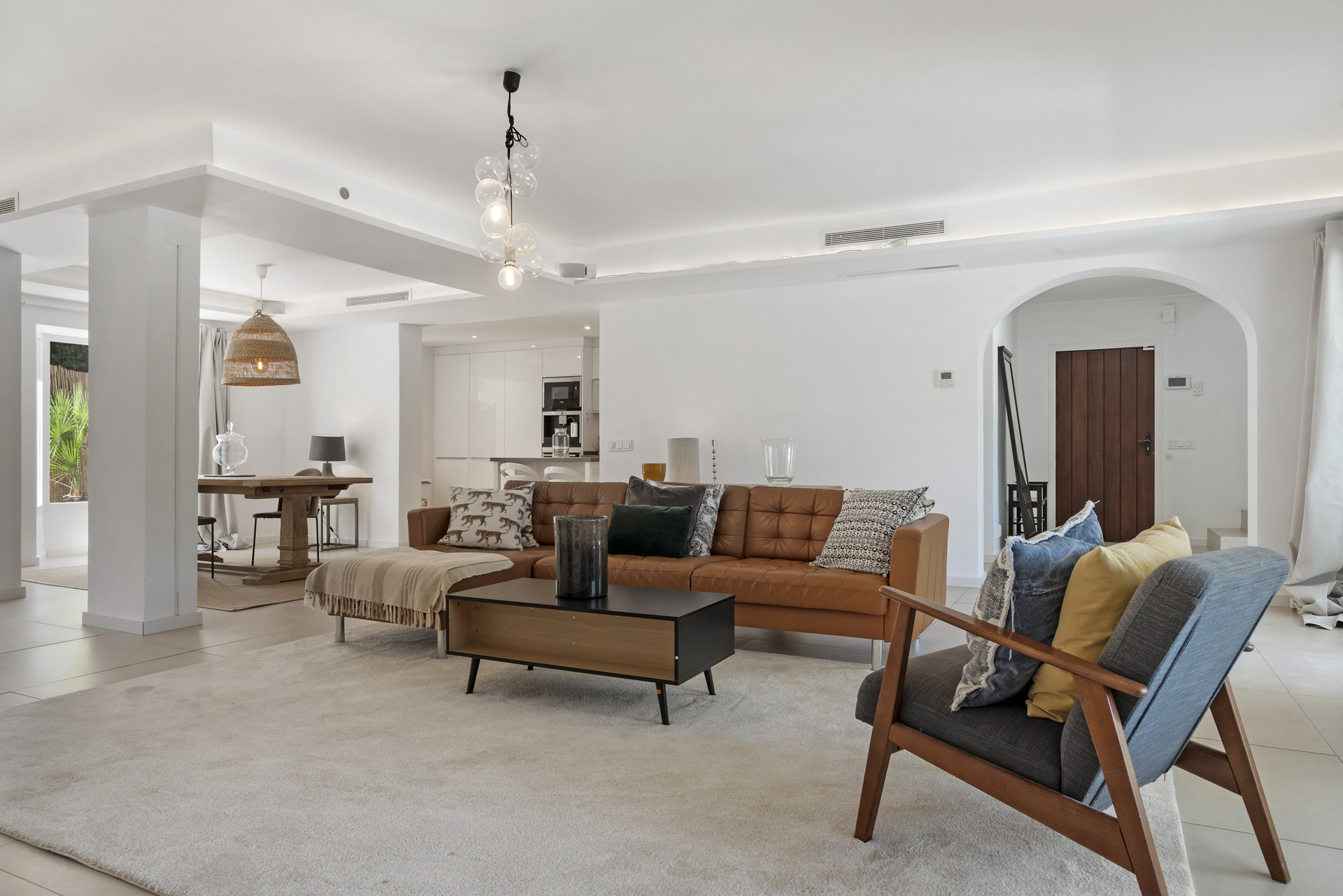 Open plan living room with brown leather sofa, wood coffee table, and dining area.