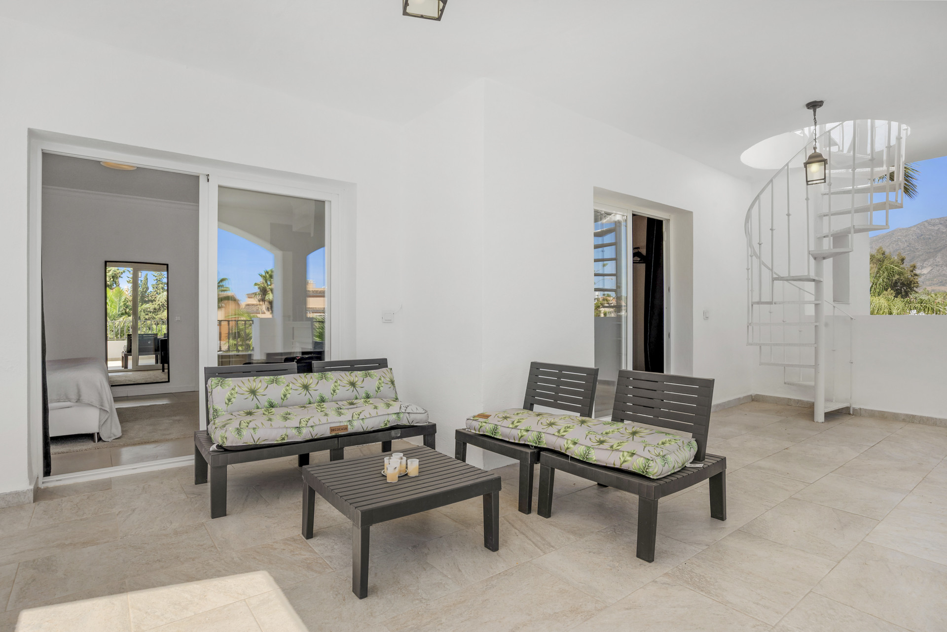 Outdoor patio with dark patio furniture, a small table, and a spiral staircase leading upstairs.