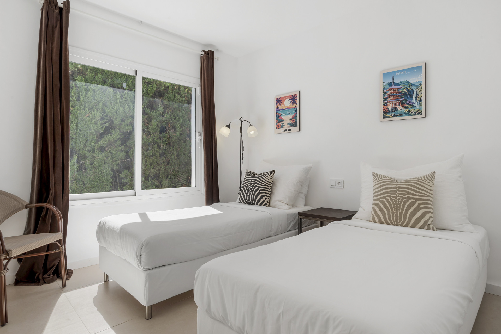 Bedroom with two single beds, white bedding, a large window, and decorative posters.
