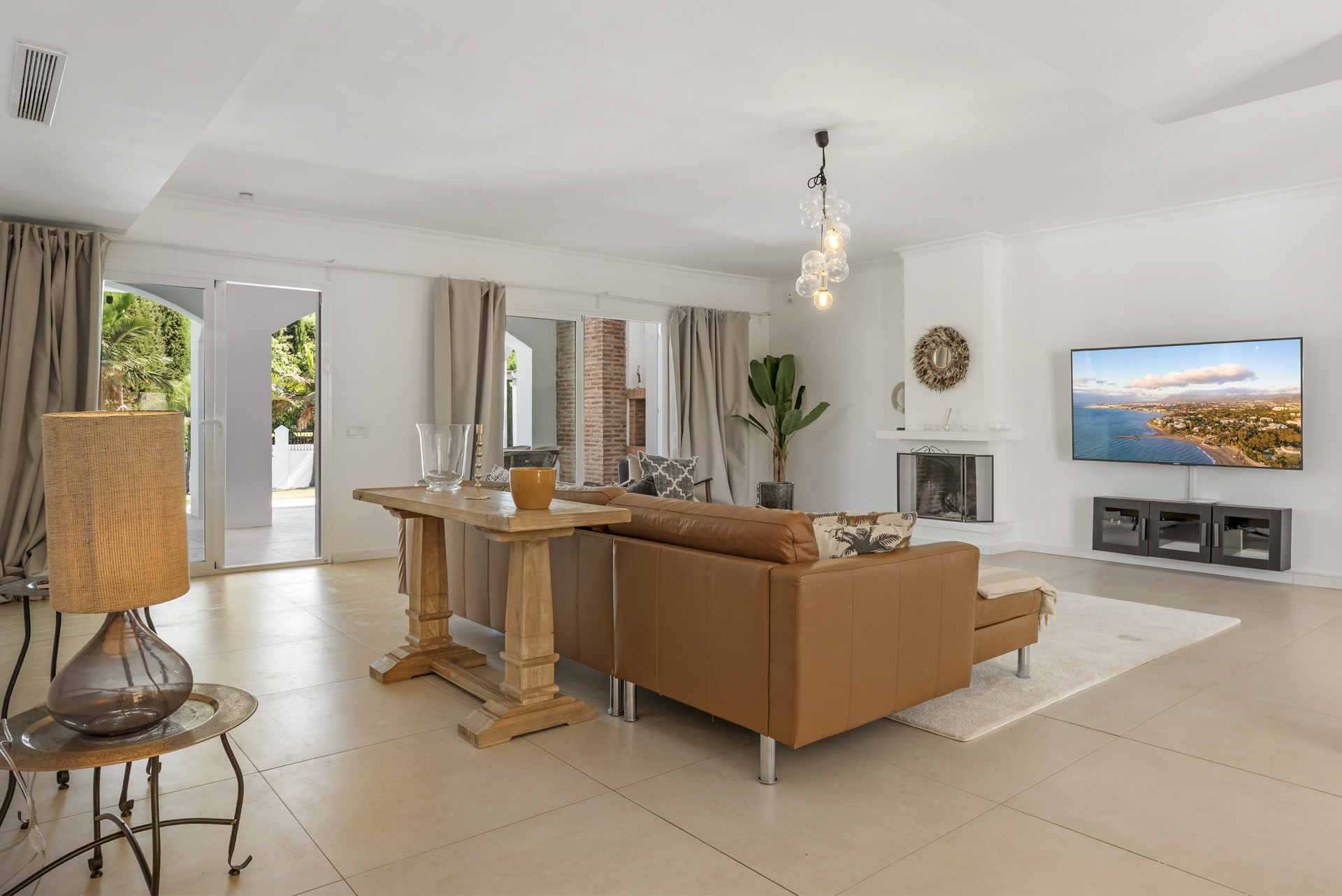 Living room with large TV, fireplace, and glass doors opening to outdoor patio.