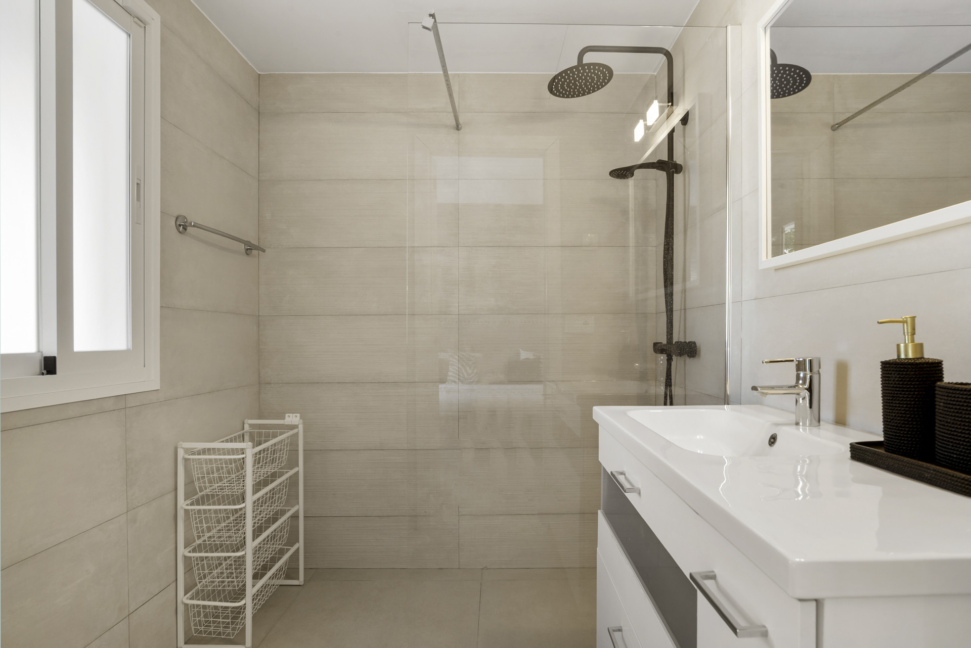 Light-tiled bathroom with a glass shower, black fixtures, modern vanity, and a small window.