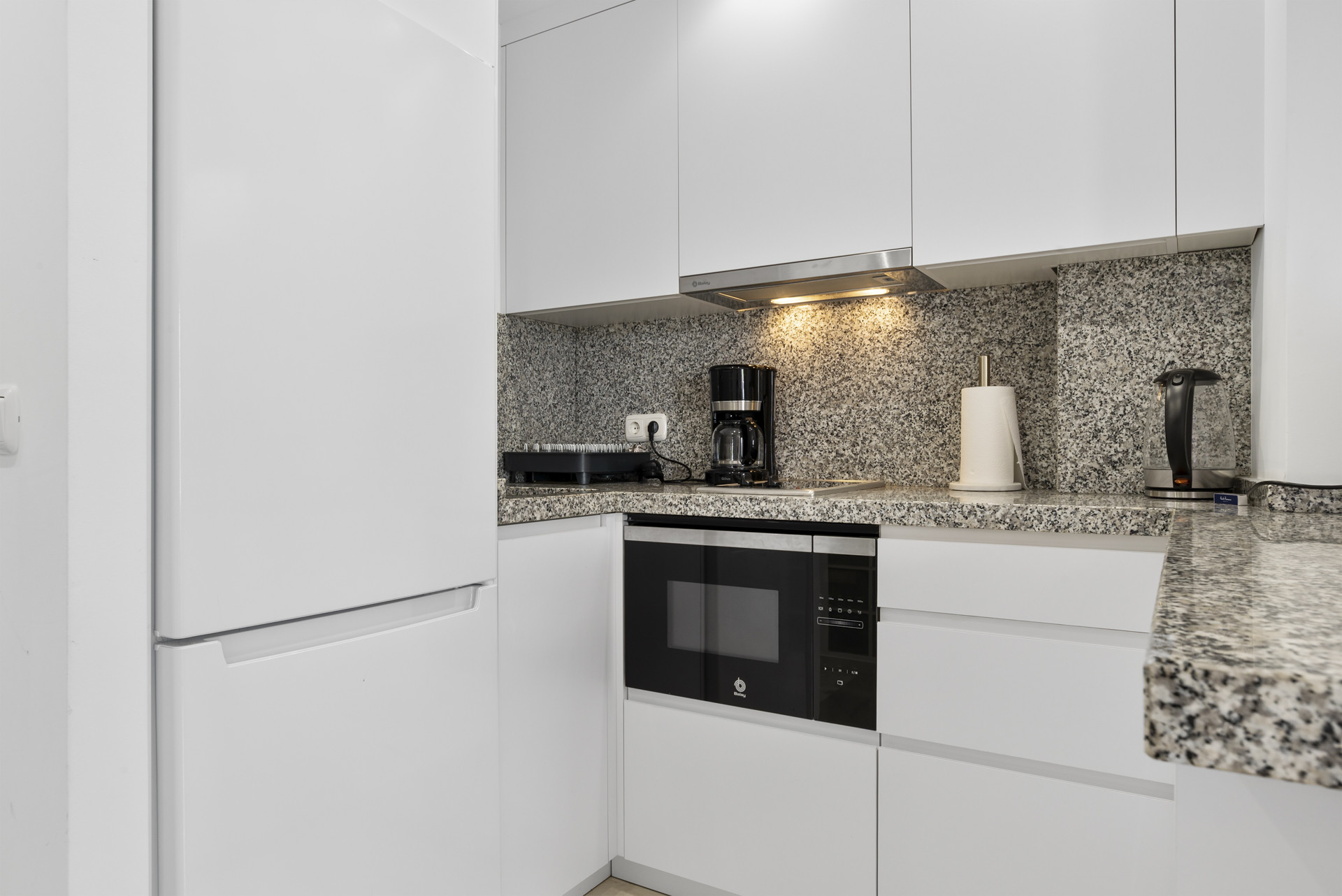 Kitchen overview highlighting white refrigerator, coffee maker, and built-in appliances.
