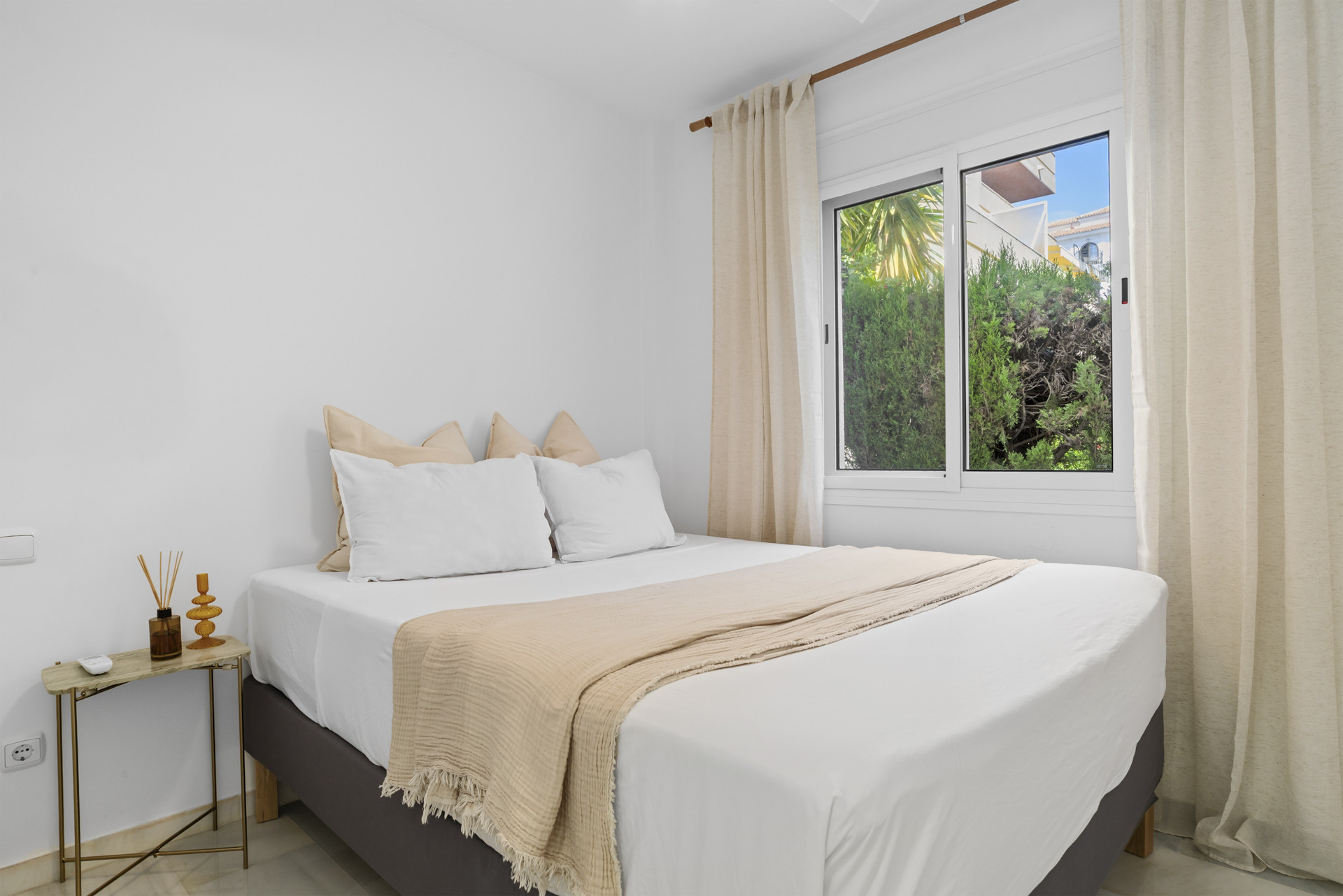Cozy bedroom featuring a large bed and a window overlooking greenery.
