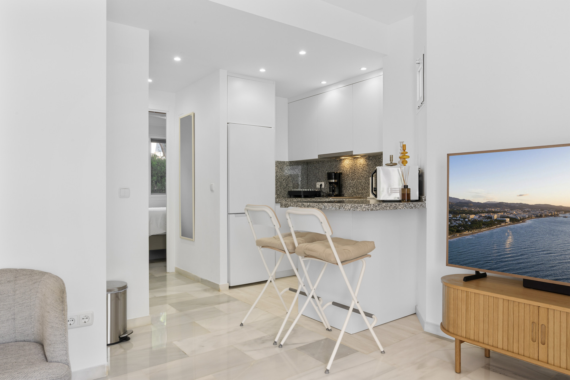 Kitchen area featuring white cabinets, a bar with stools, and open to the living space.