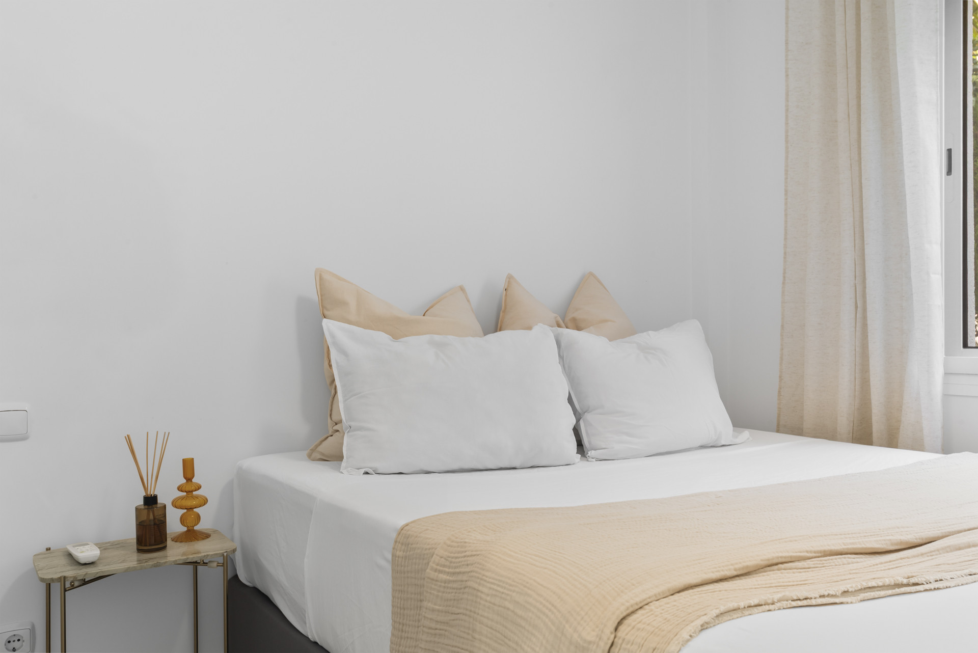 Close-up of a bed with decorative pillows and a side table.