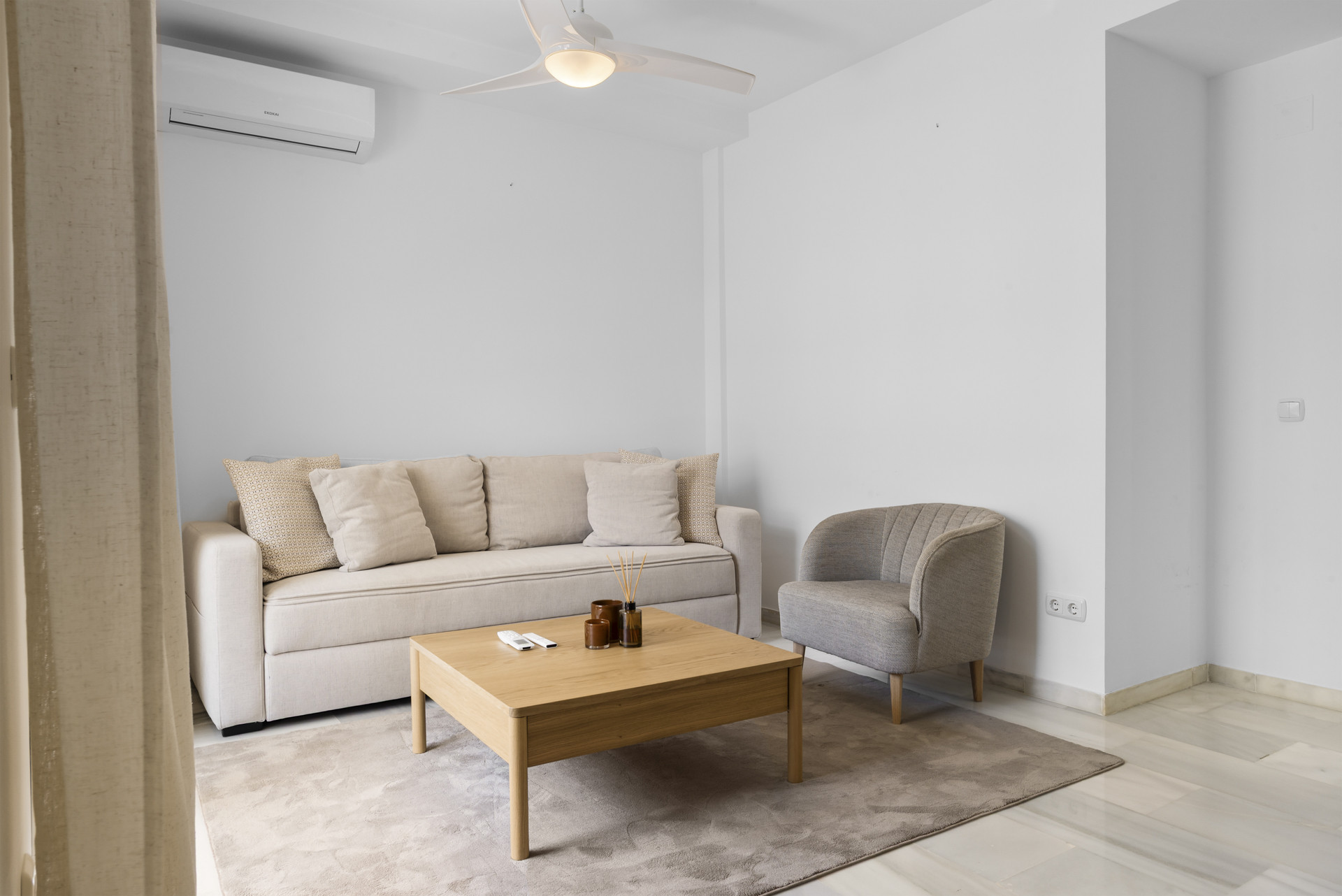 Angle of the living room showcasing seating and airy decor.