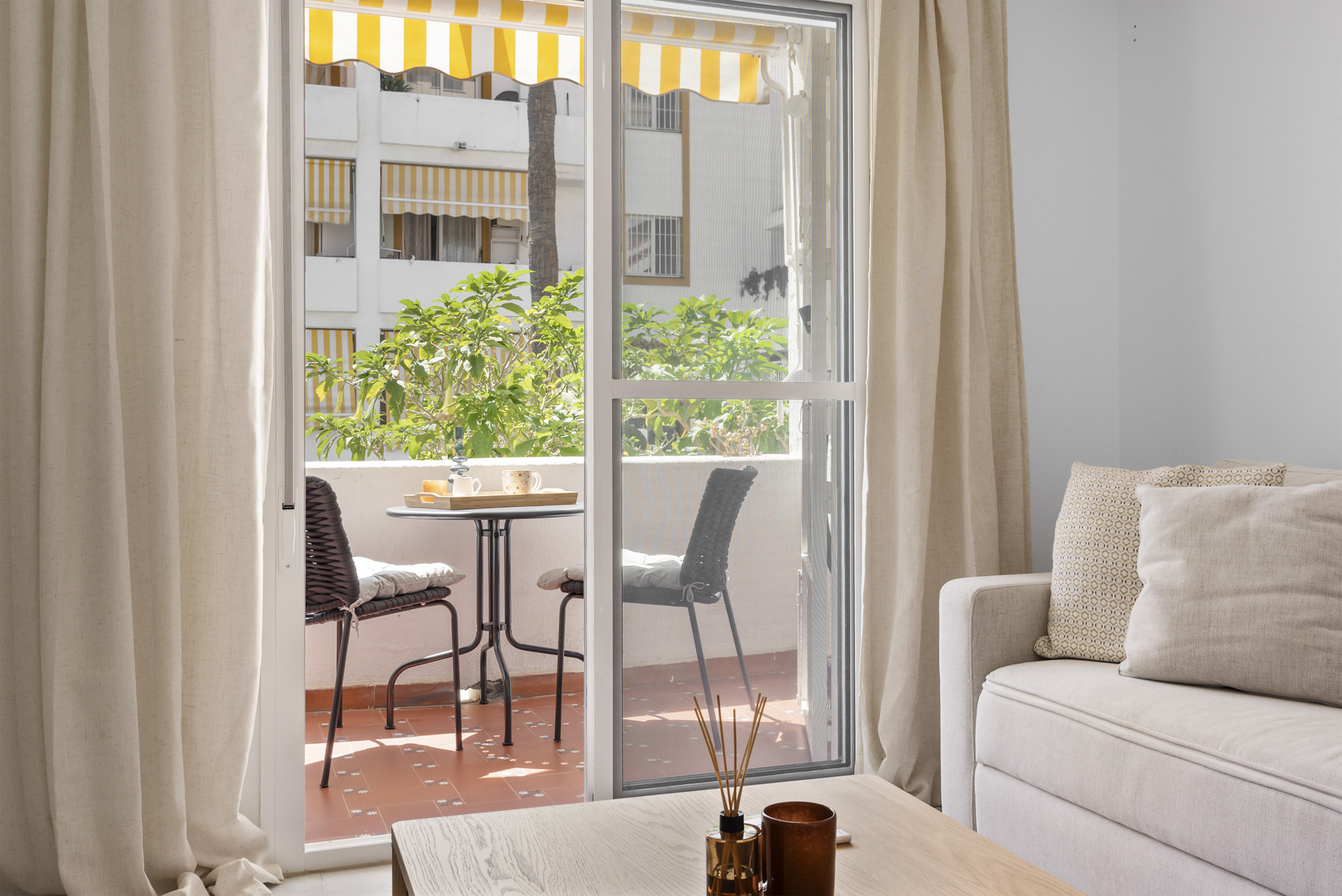 Bright living area with curtains and view of outdoor seating on the balcony.