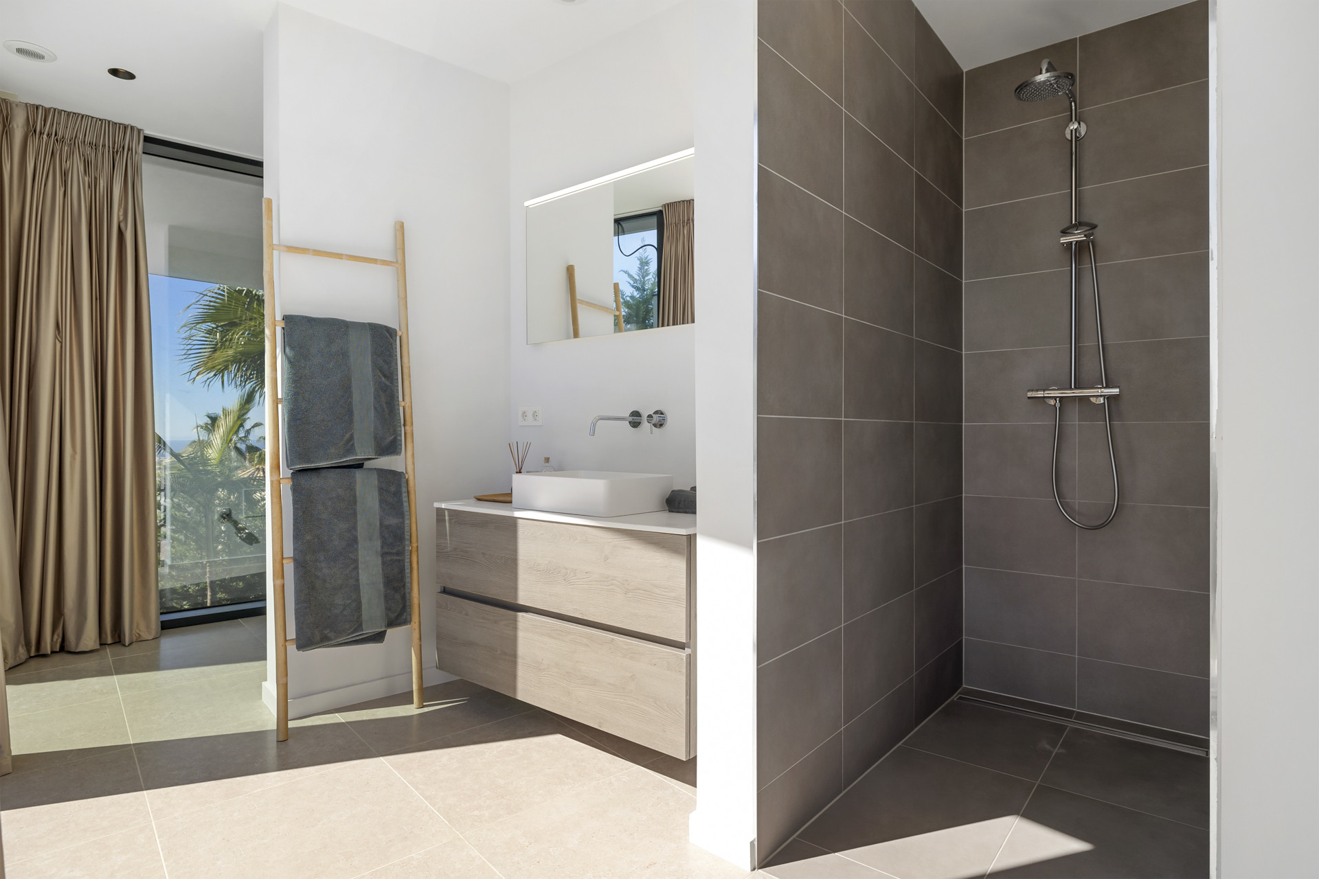 Modern bathroom with a walk-in shower, wooden vanity with sink, and a large mirror.