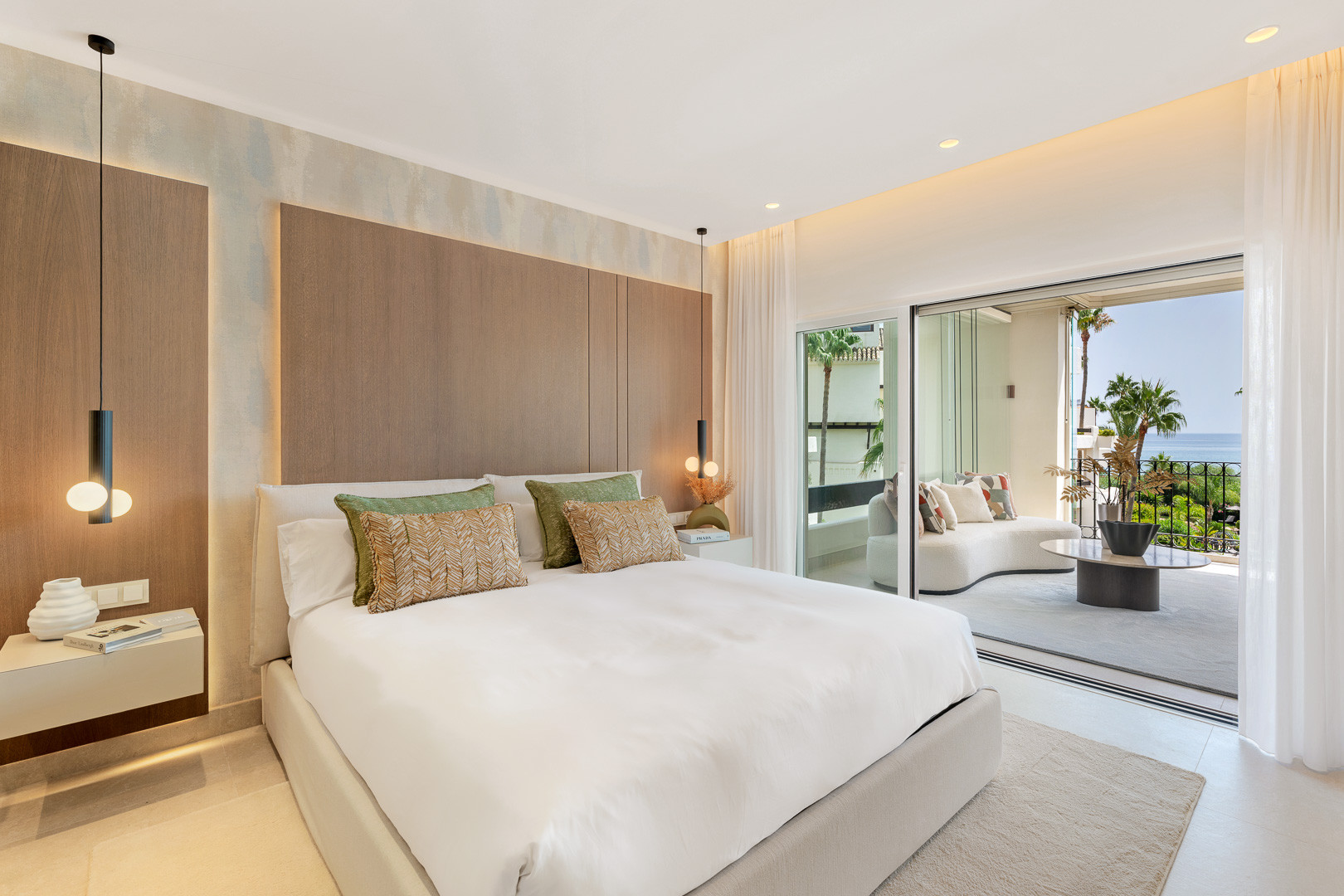 Bedroom with a large bed, balcony access, and ocean views through sliding glass doors.