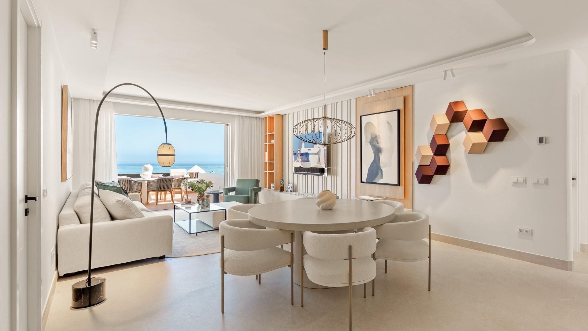 Open plan living and dining area with round table, sofa, and outdoor terrace beyond.