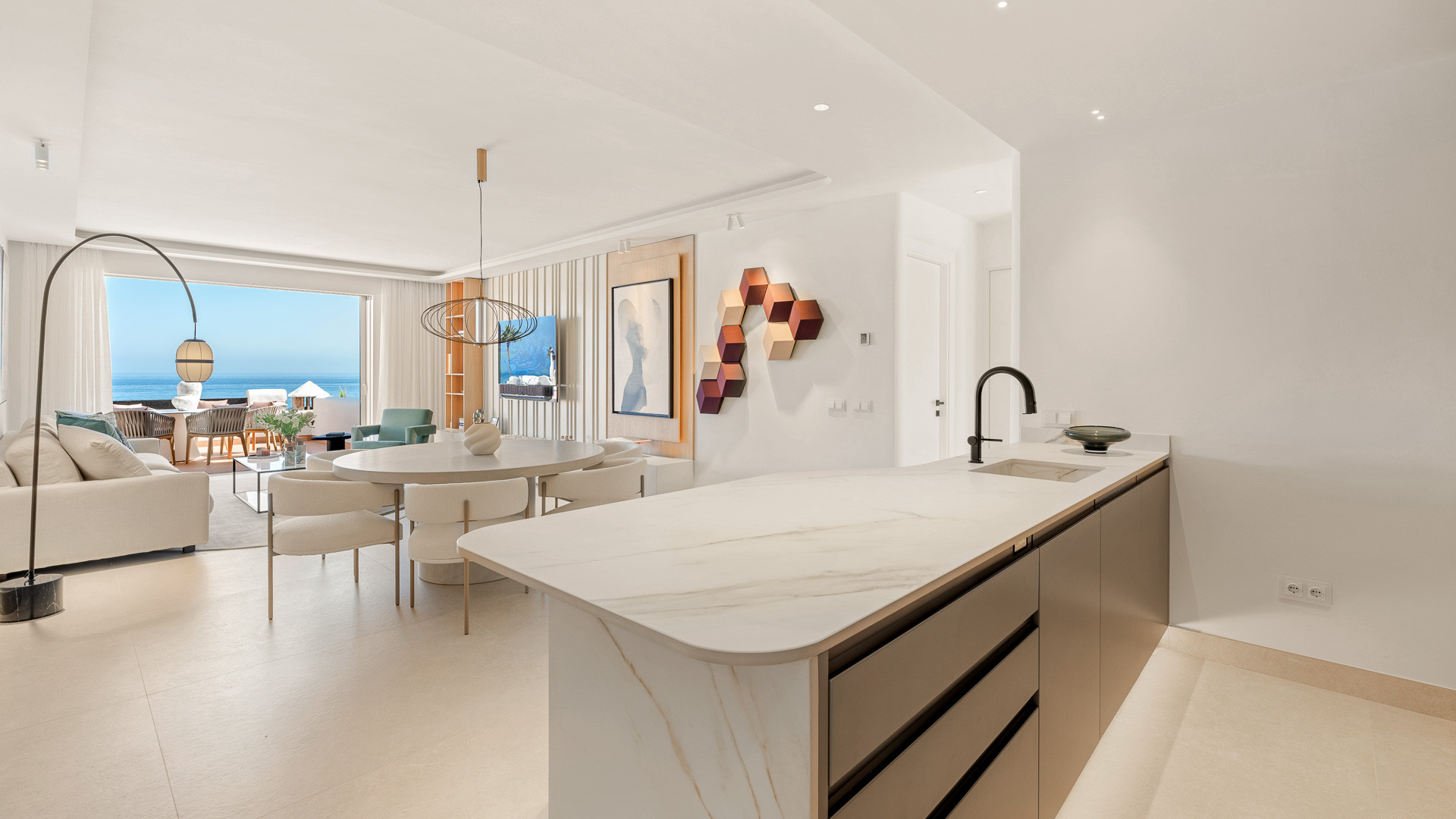 Open plan kitchen island, dining table, and living room with ocean view balcony.