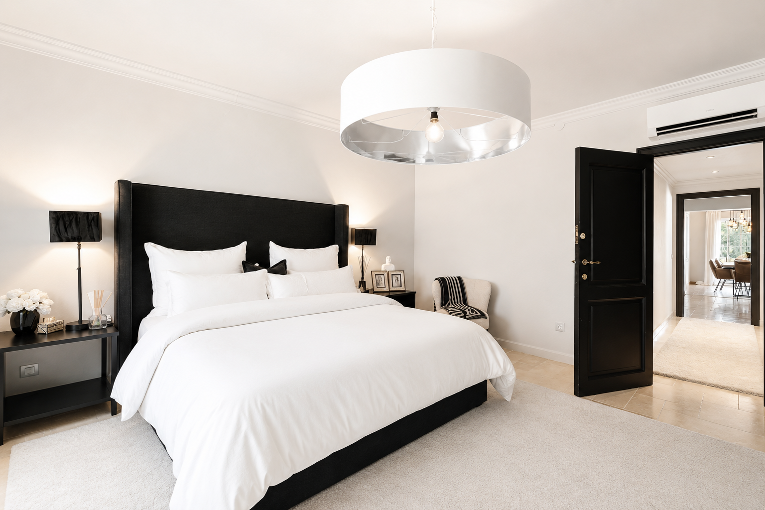 Inviting master bedroom with a plush bed, black accents, and natural light from a door leading outside.