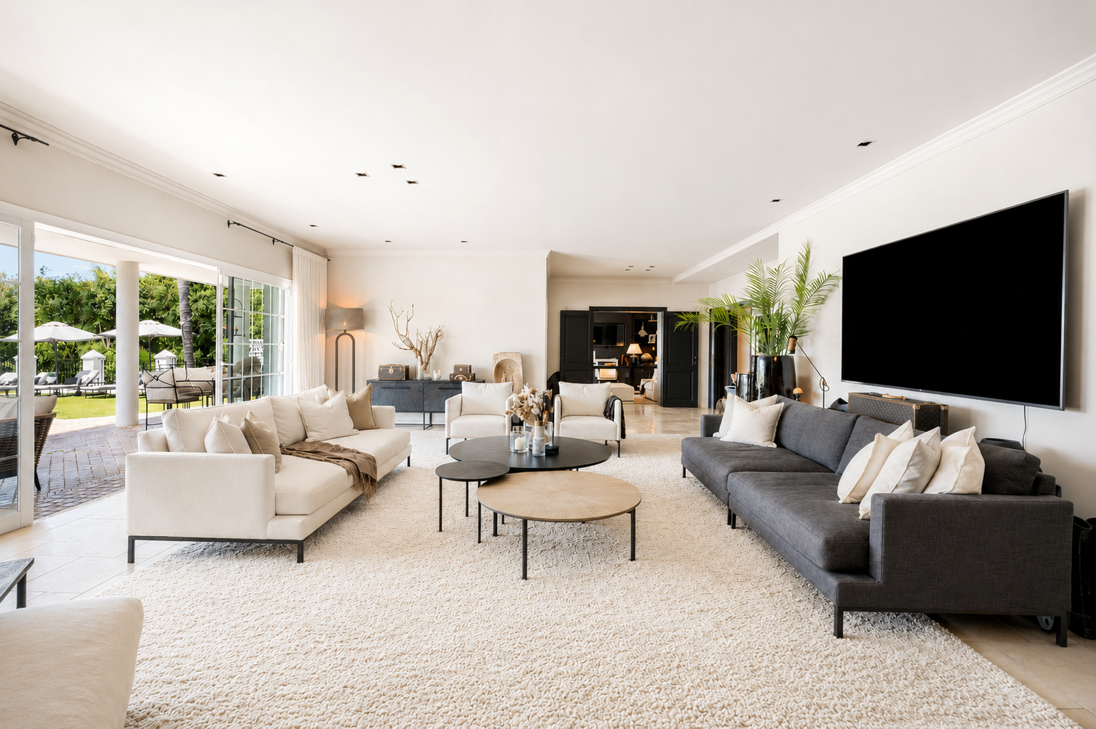 Bright living room with sofas, rugs, and view of the outdoor area through large windows.