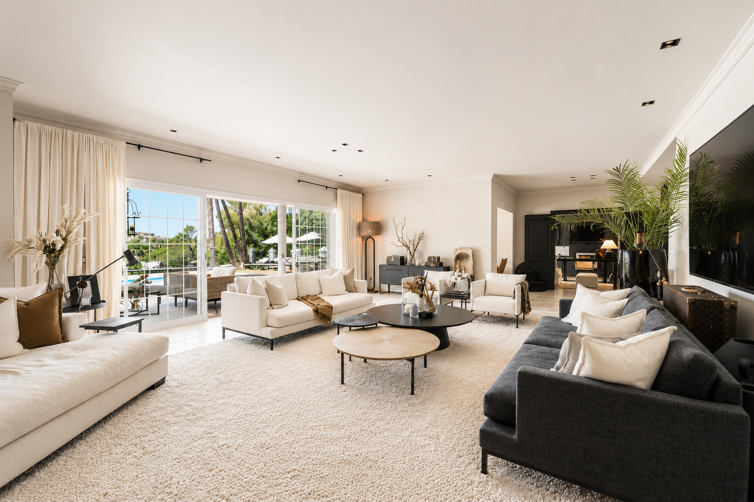 Bright living room with white sofas, a coffee table and large windows looking out to the garden.