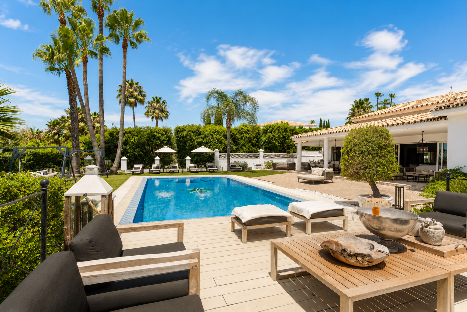 Outdoor seating area by the pool with sun loungers and umbrellas.