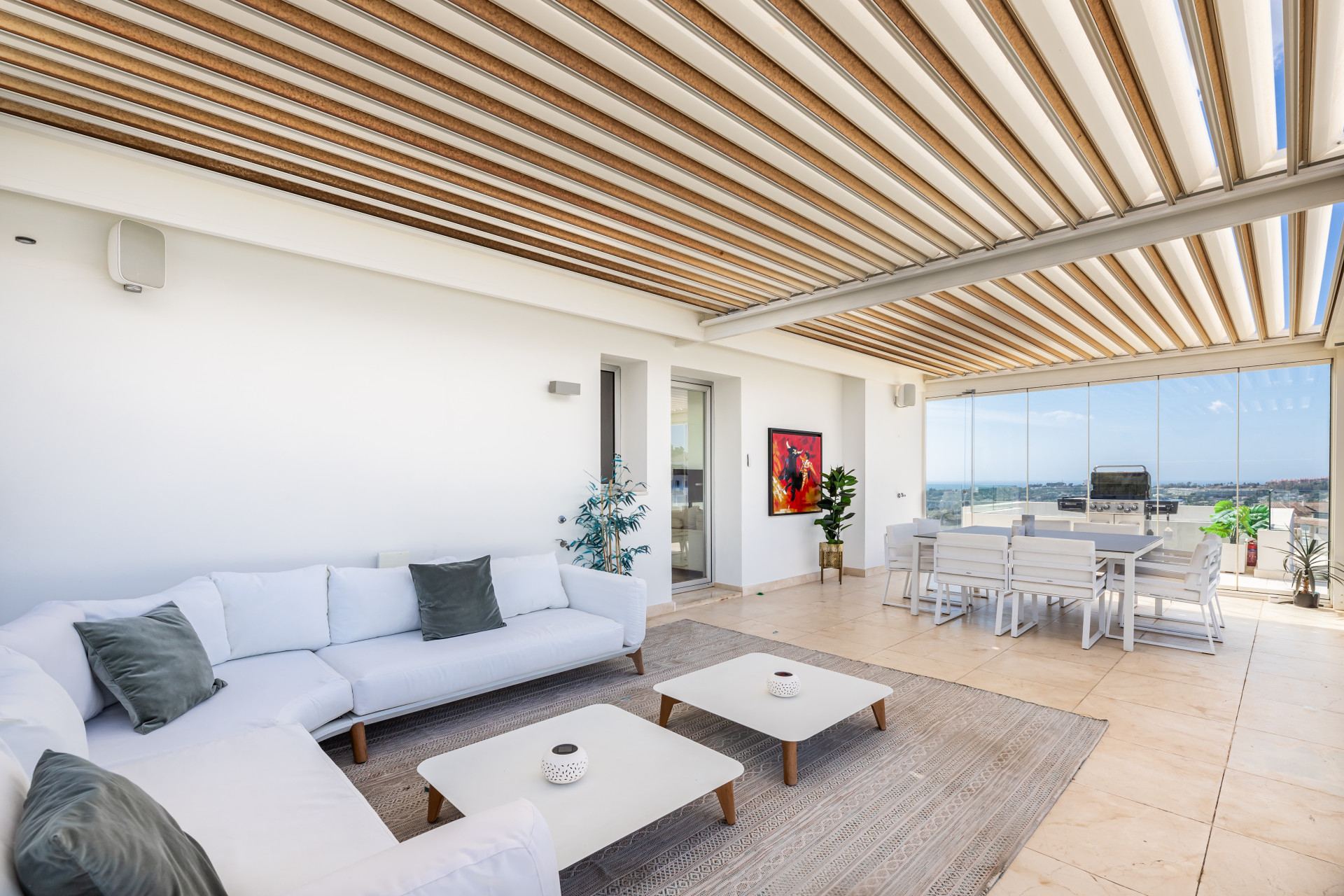 Lounge area with light decor, dining setup, and a barbeque grill accessible from the terrace.