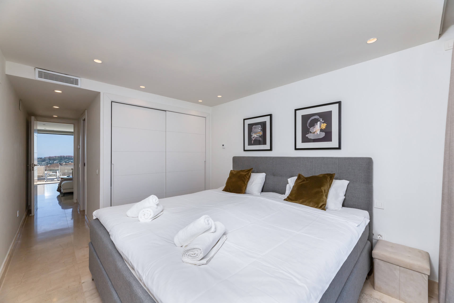 Secondary bedroom featuring a double bed, artwork on the walls, and a doorway leading to the hallway.