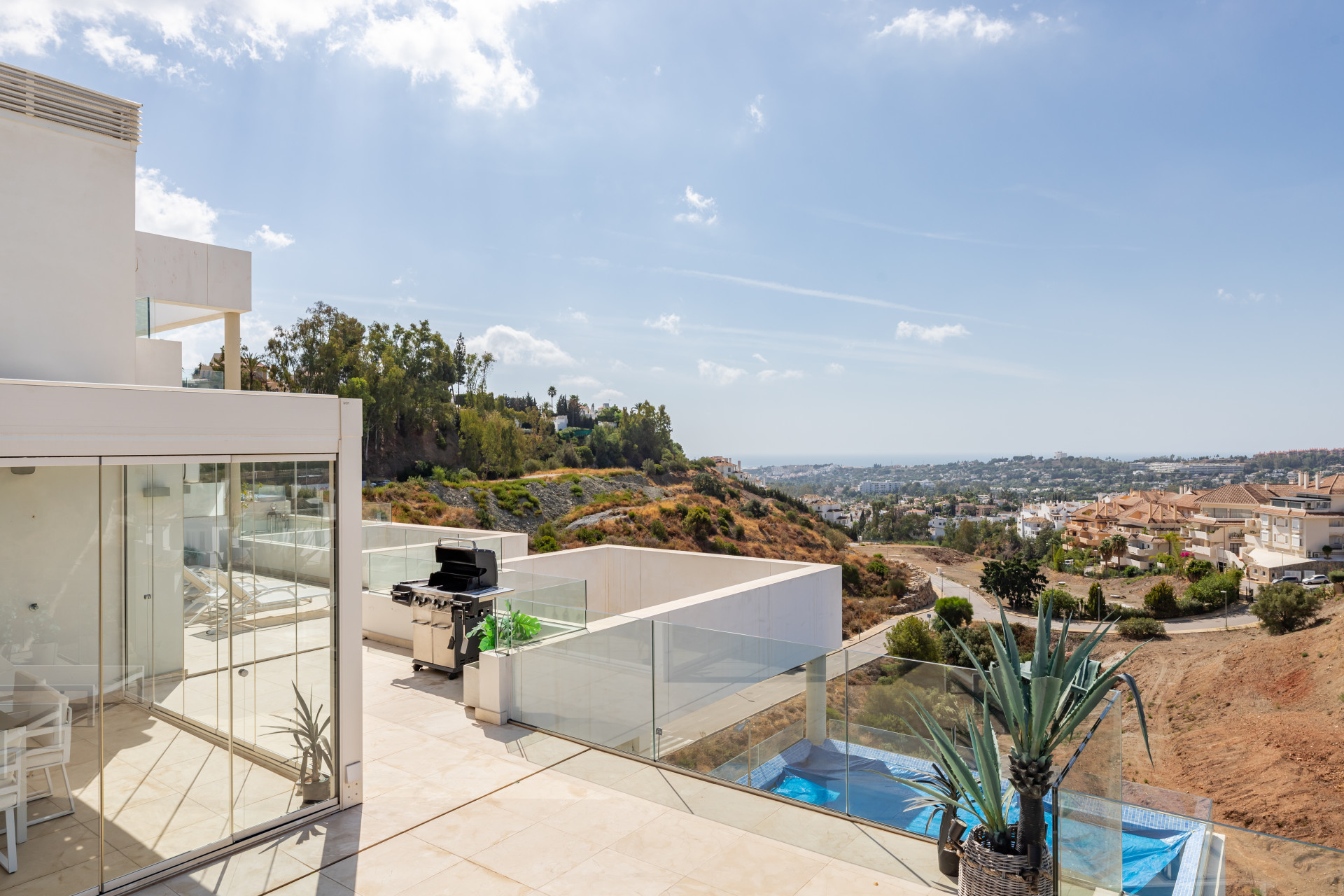 Exterior view of the terrace with glass features and distant view of Marbella's hillside.