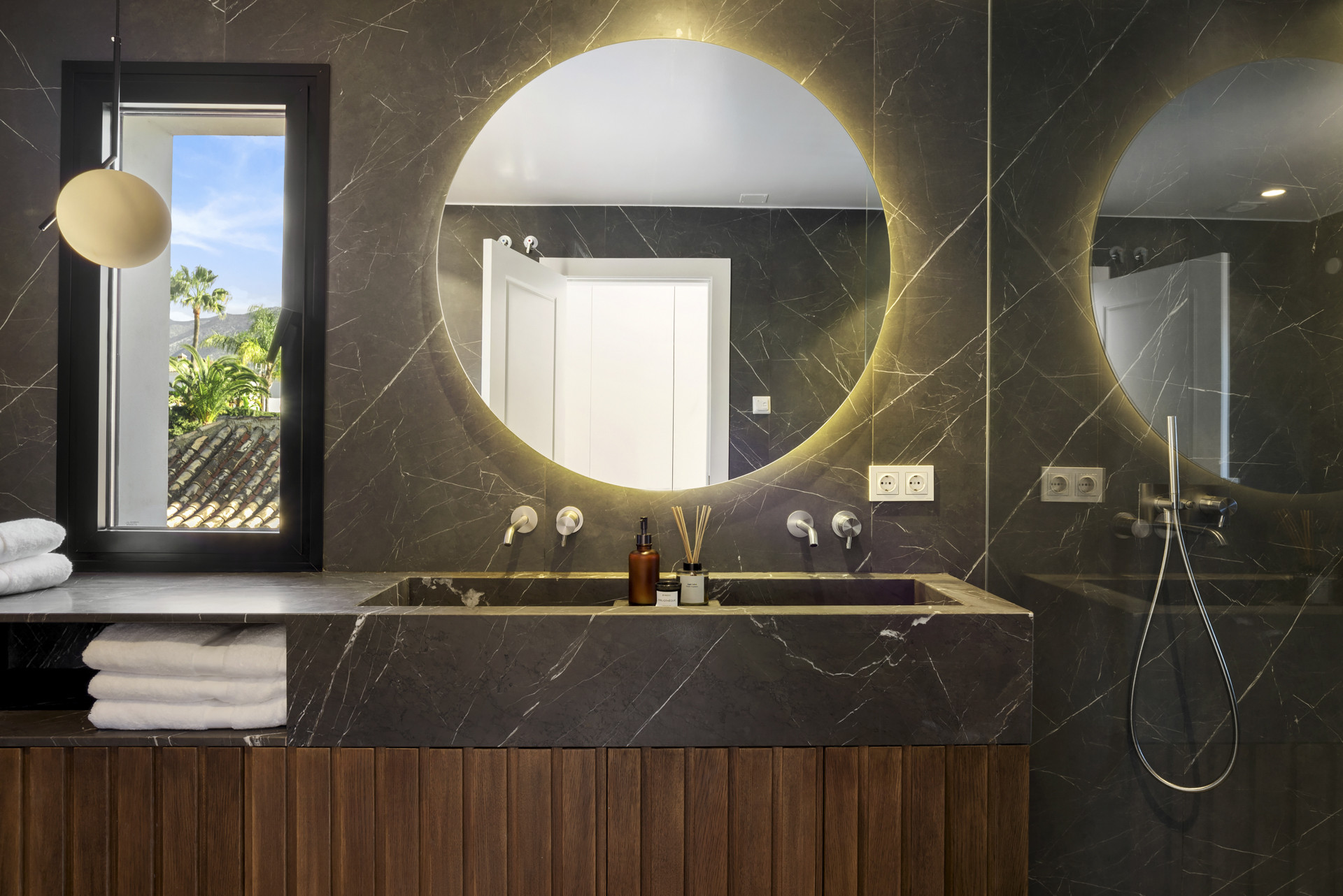 Modern bathroom featuring round mirrors, stylish sink, and a window view.