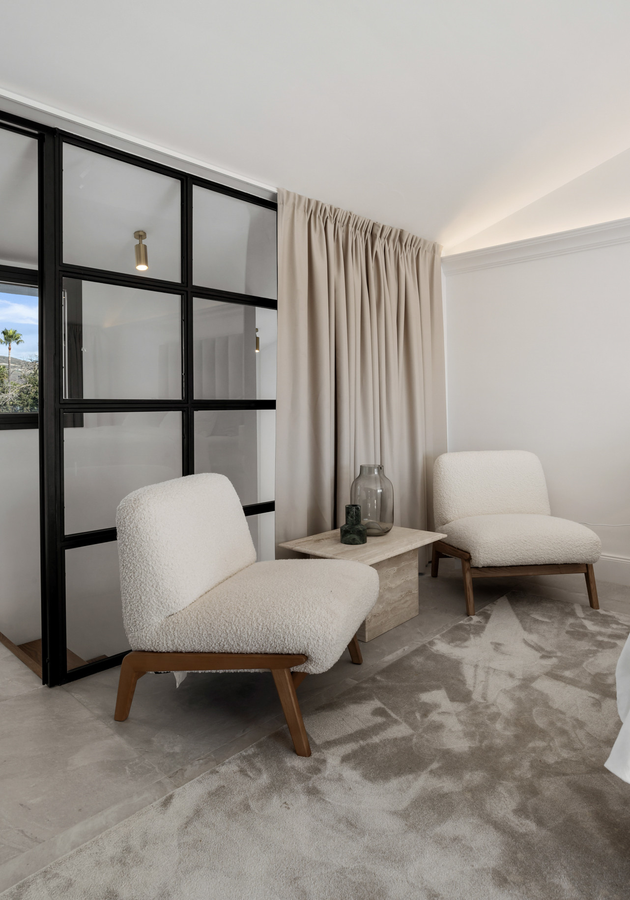 Cozy seating area with two chairs, small table, curtains, and glass partition.