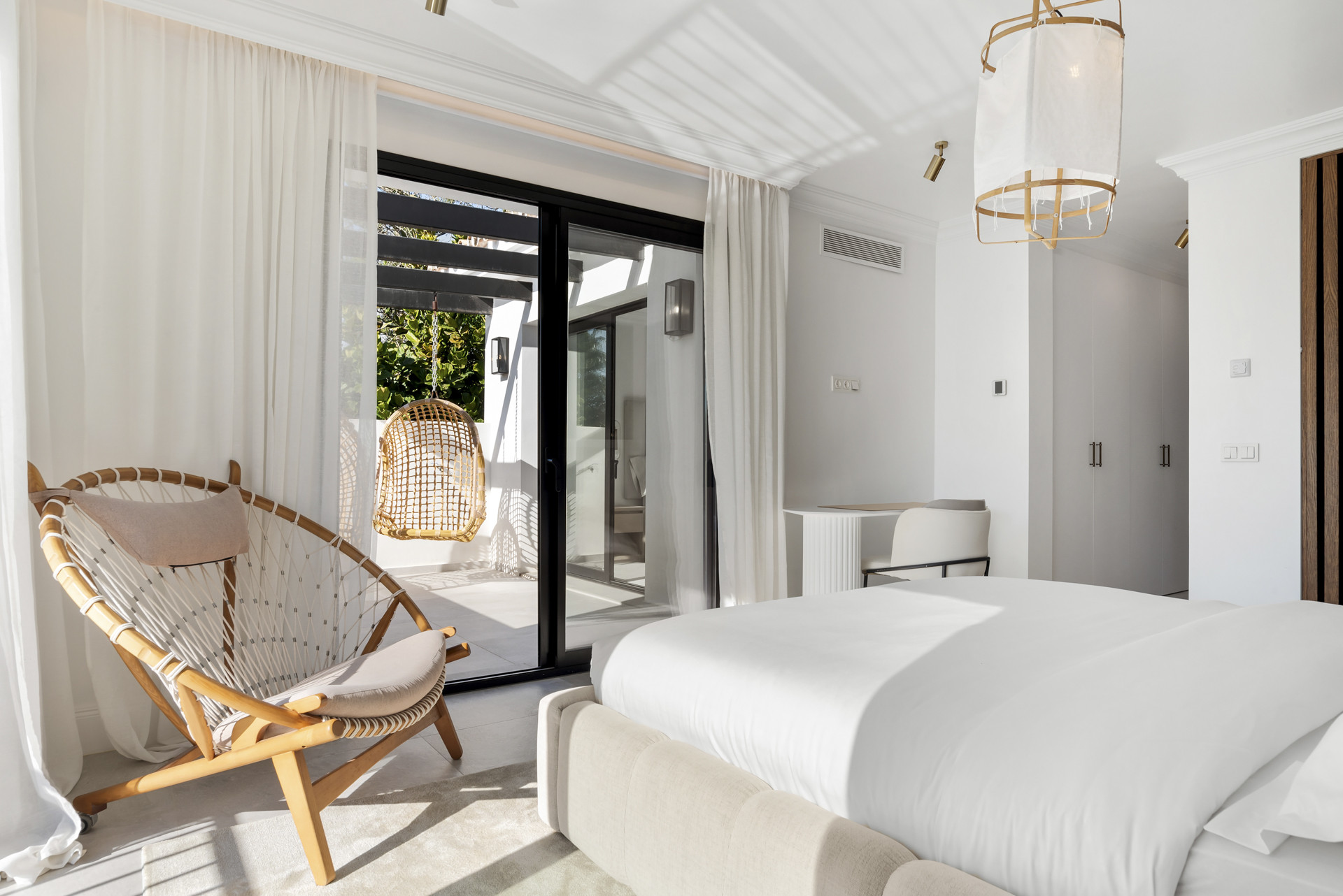 Bedroom with a hanging chair and open patio door leading outdoors.