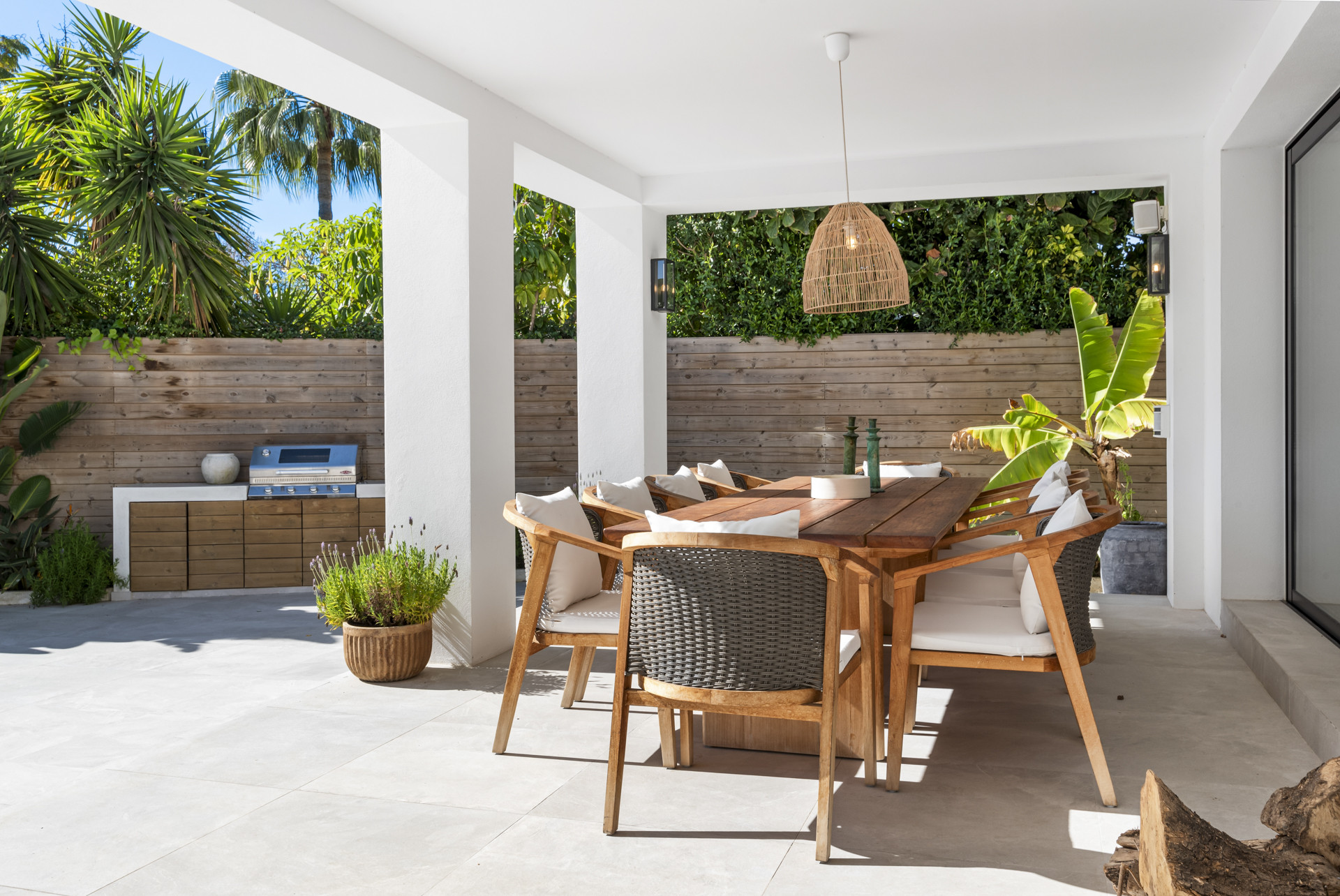Covered dining space featuring a grill and tropical plants.