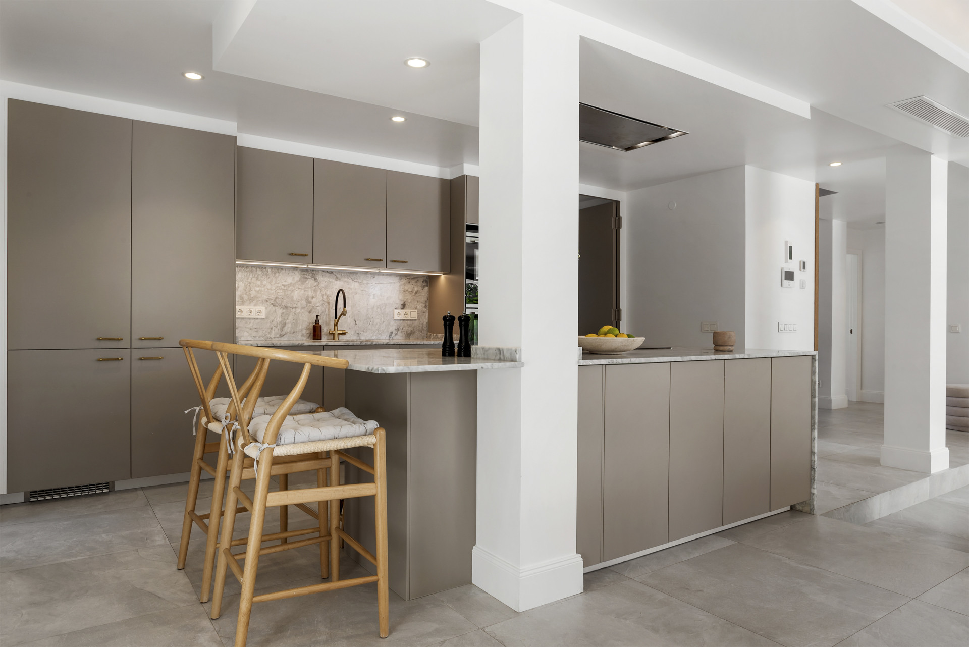 Contemporary kitchen with sleek cabinets, marble countertops, and bar seating by a stylish partition.