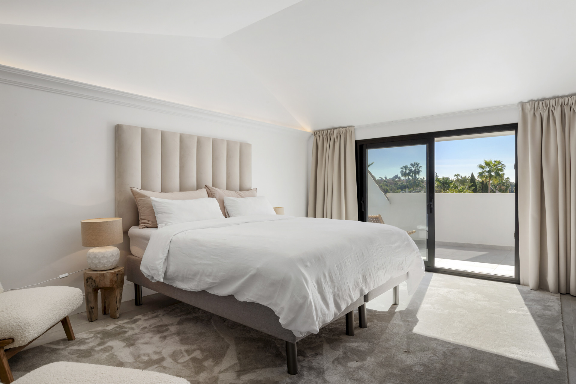 Spacious bedroom with vaulted ceiling and sliding glass door to a balcony.