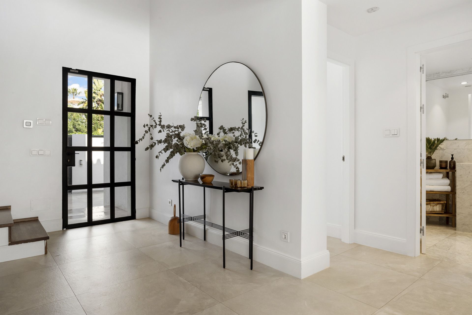 Entryway with a round mirror and decorative vase on a console table