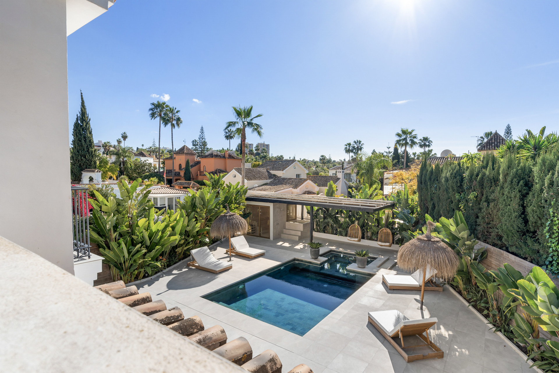 View of pool area with sun loungers and thatched umbrella