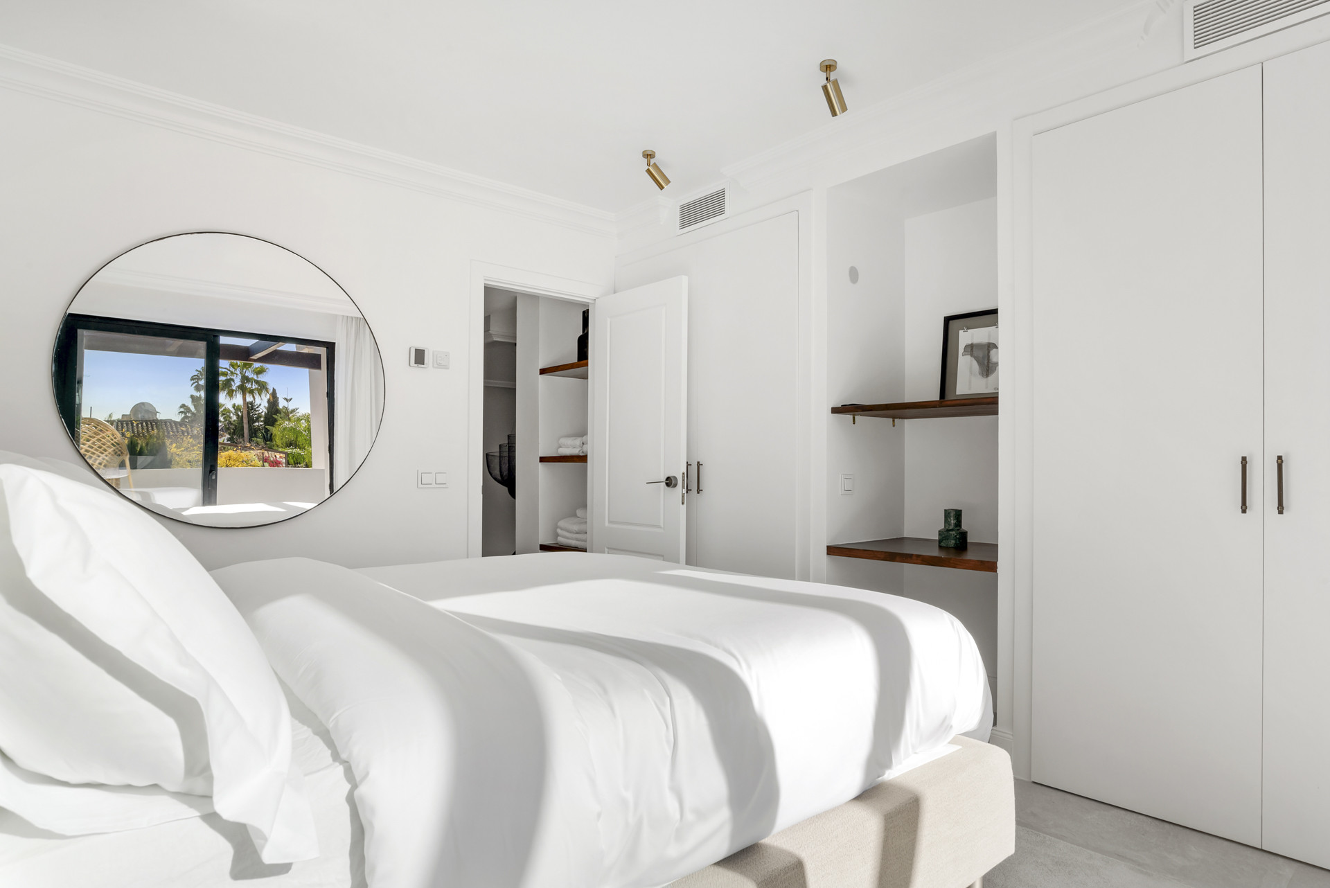 Bedroom featuring a round mirror, closet, and natural light through the window.