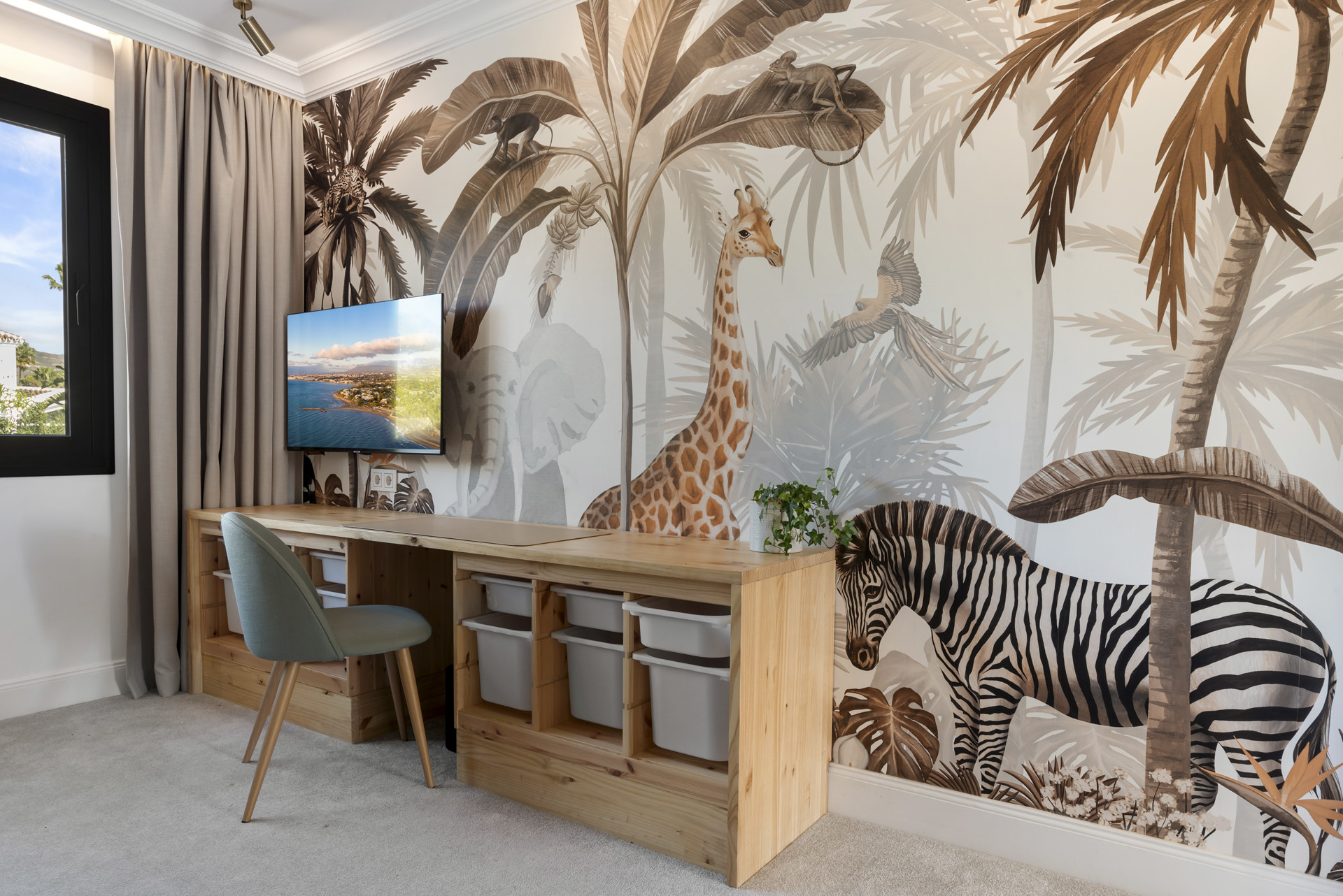 Colorful animal-themed wallpaper with desk, chair, and TV against the wall.