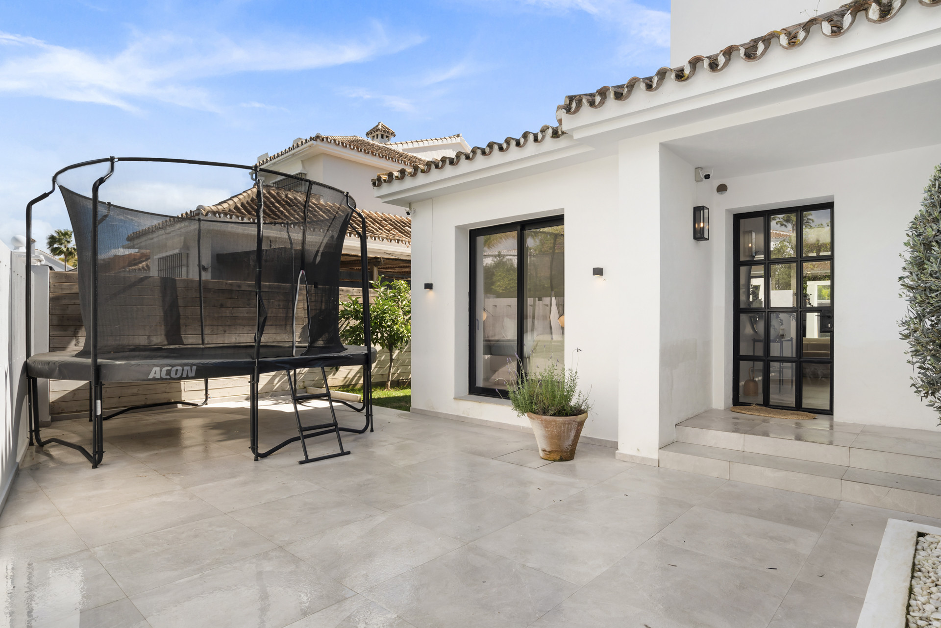 Trampoline positioned next to the house, with steps leading to the entrance.
