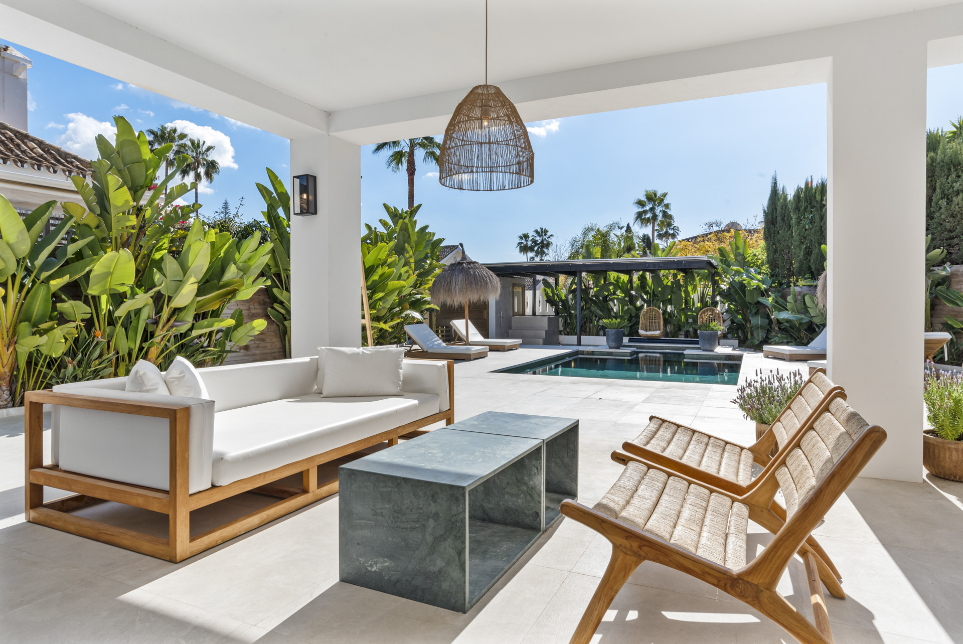 Lounge area with white couch and marble table overlooking the pool.