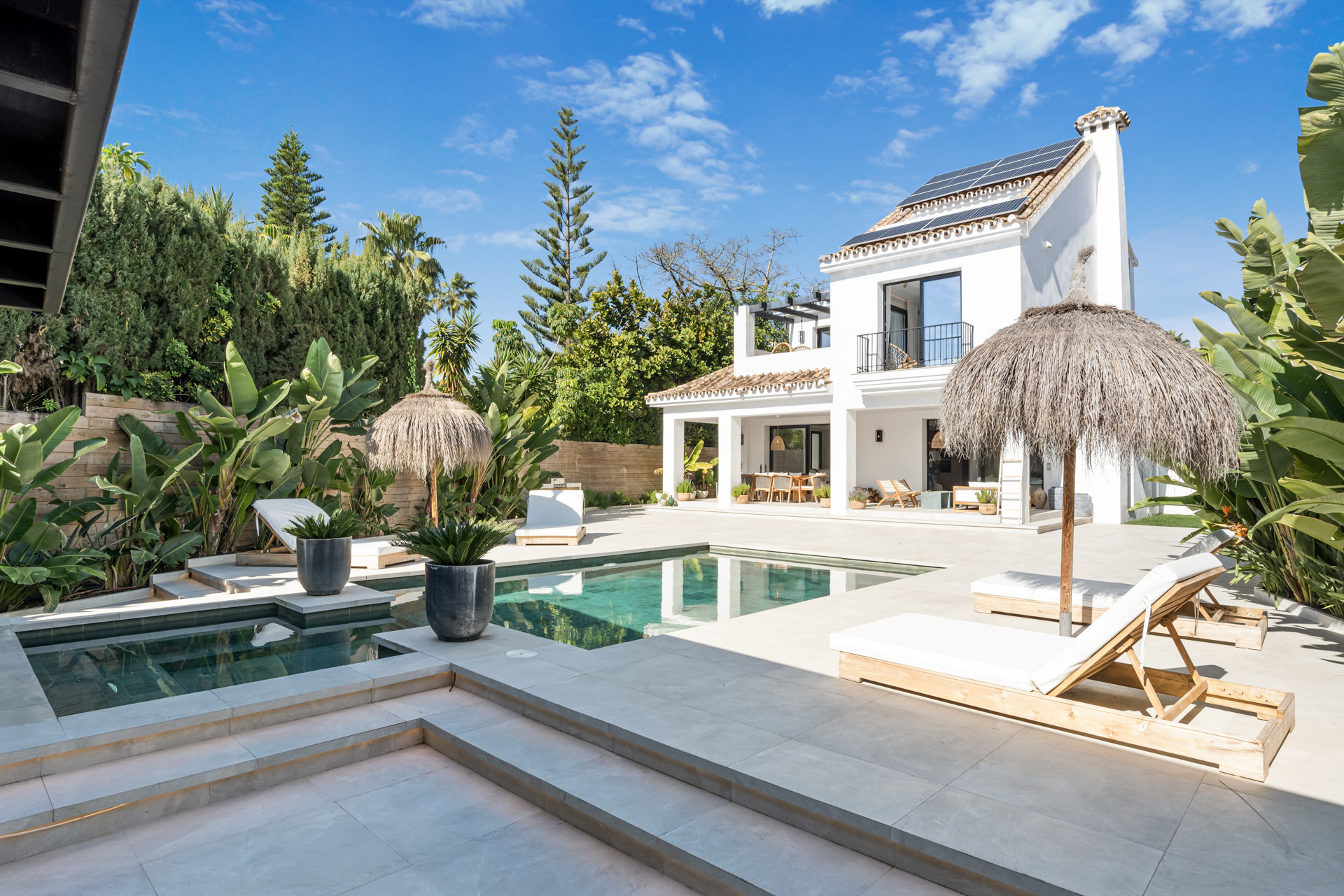 Wide shot of the outdoor space with the villa, loungers, and green surroundings.