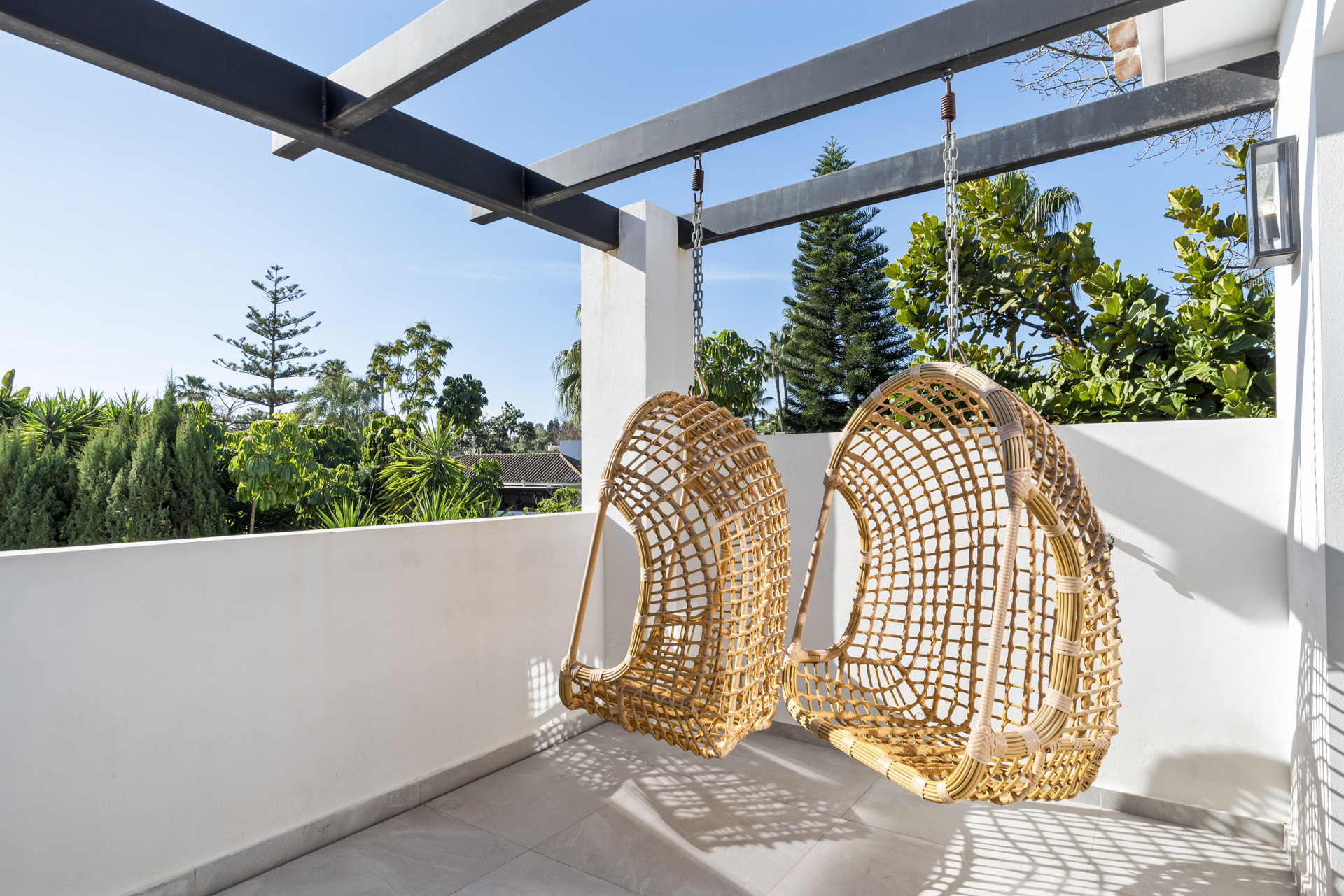 Outdoor area with hanging chairs and landscaped greenery