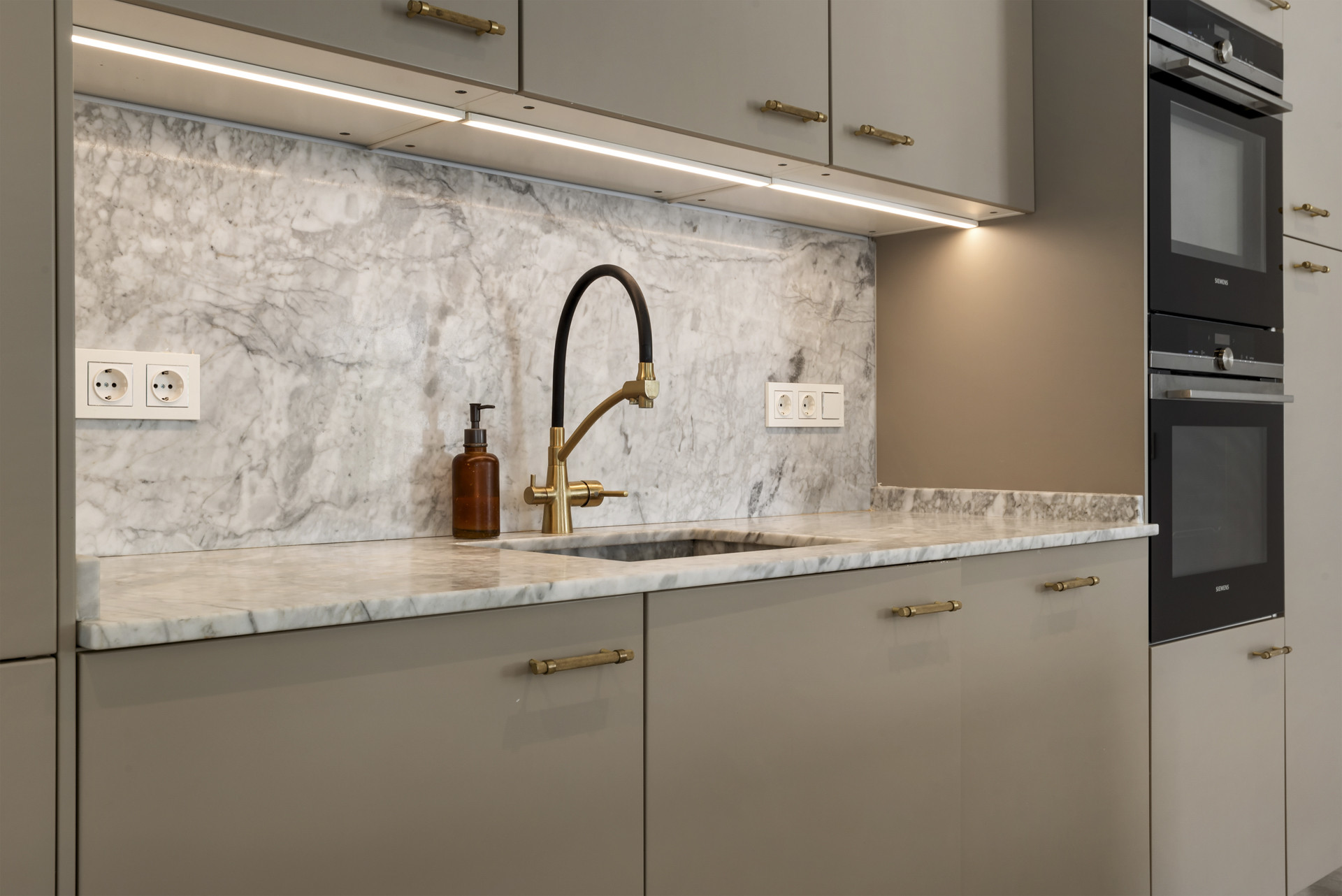 Close-up of kitchen sink area with marble backsplash and modern faucet.